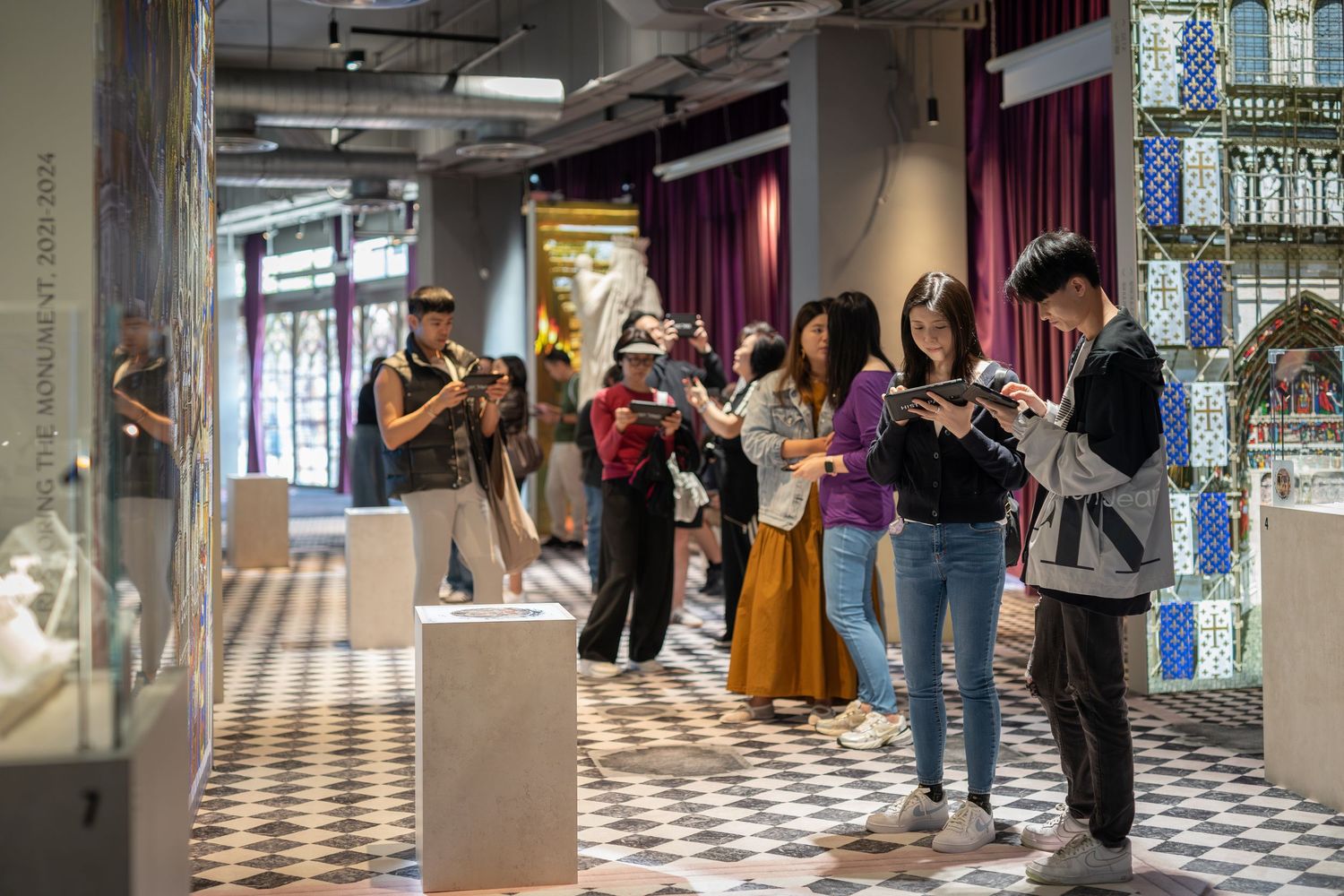 Visitors exploring an art museum gallery with sculptures and decorative tile walls on display.