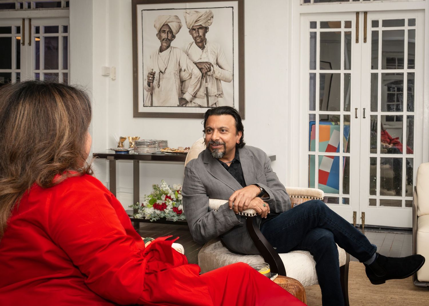 Man in grey blazer having an interview conversation in a stylishly decorated living room.