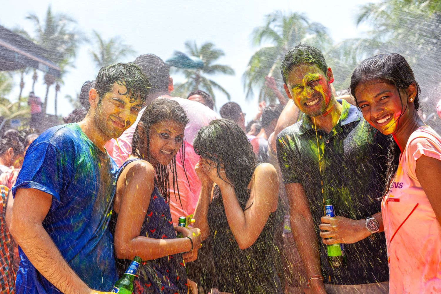 Friends celebrating Holi festival covered in colorful powder and water outdoors.