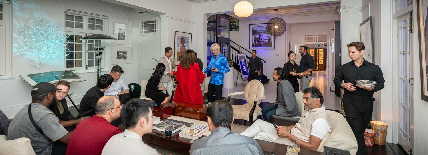 Guests mingle and socialize at an elegant indoor evening gathering in a stylish white room with modern decor.