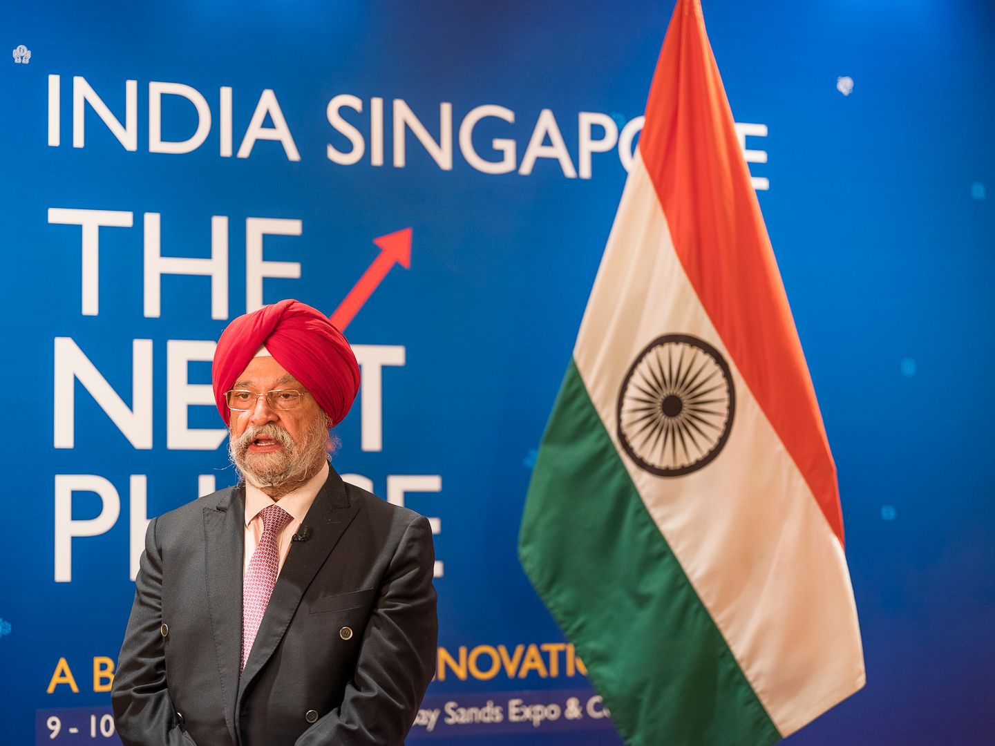 Indian dignitary in turban stands before Indian flag at India Singapore The Next Phase innovation event.