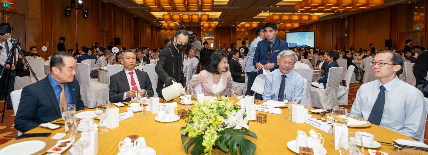 Professionals in formal attire networking at a corporate banquet event, seated at elegantly decorated round tables in a conference hall.