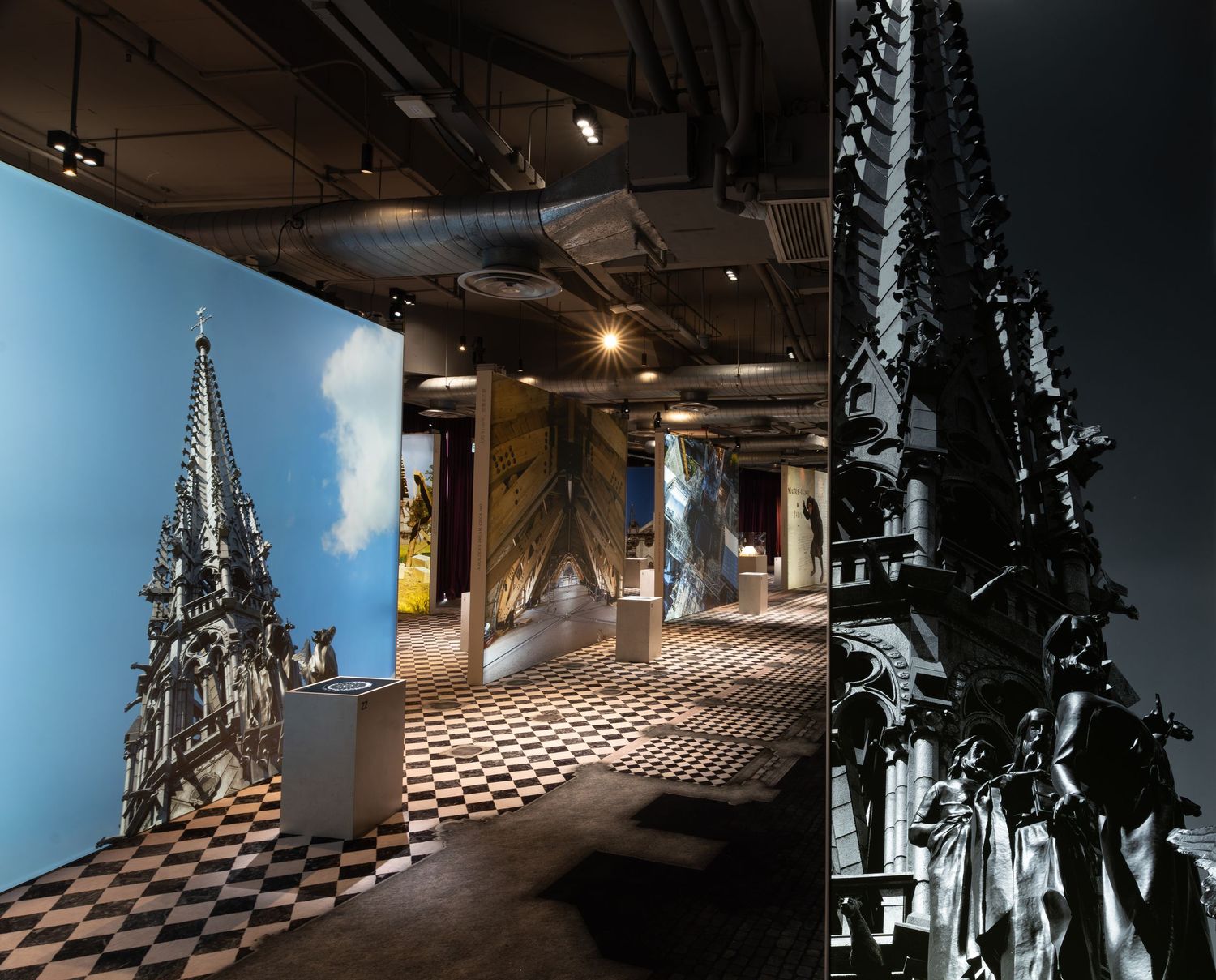 Museum exhibition hall with Gothic cathedral spire murals and checkered floor display.