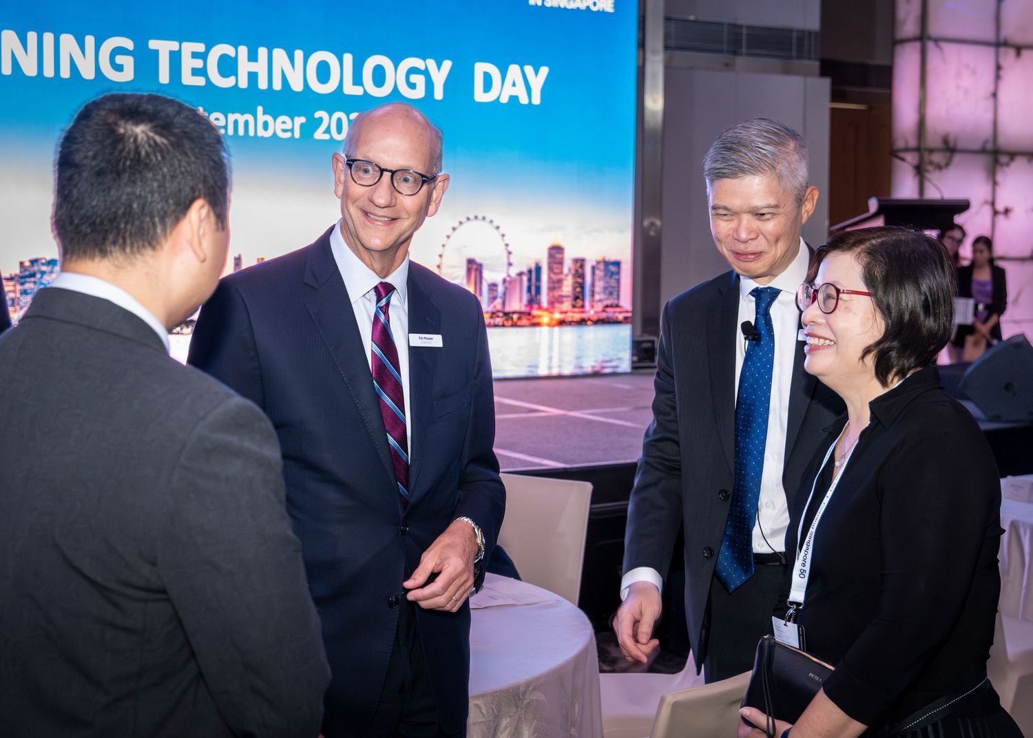 Professionals networking and conversing at a Banking Technology Day event in Singapore.
