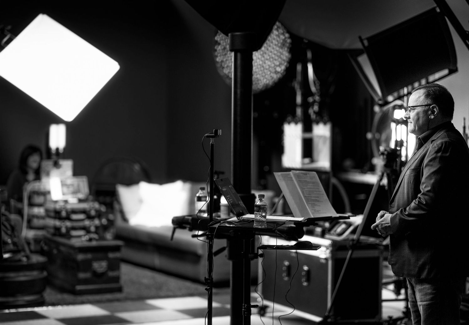 Filmmaker reviewing script on tablet in professional black and white studio behind-the-scenes photo.