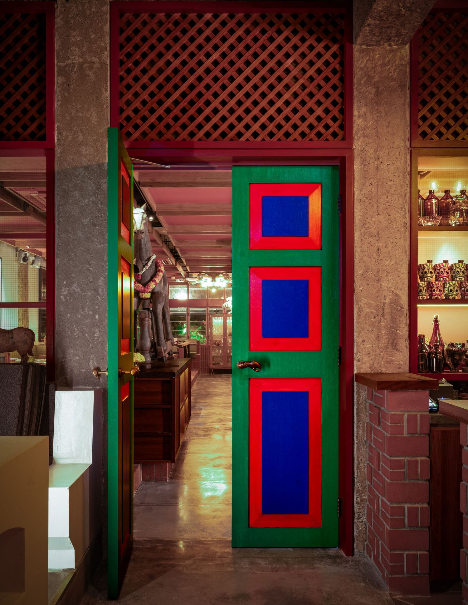 Colorful door with green frame and red-bordered blue panels in a vibrant restaurant entrance.
