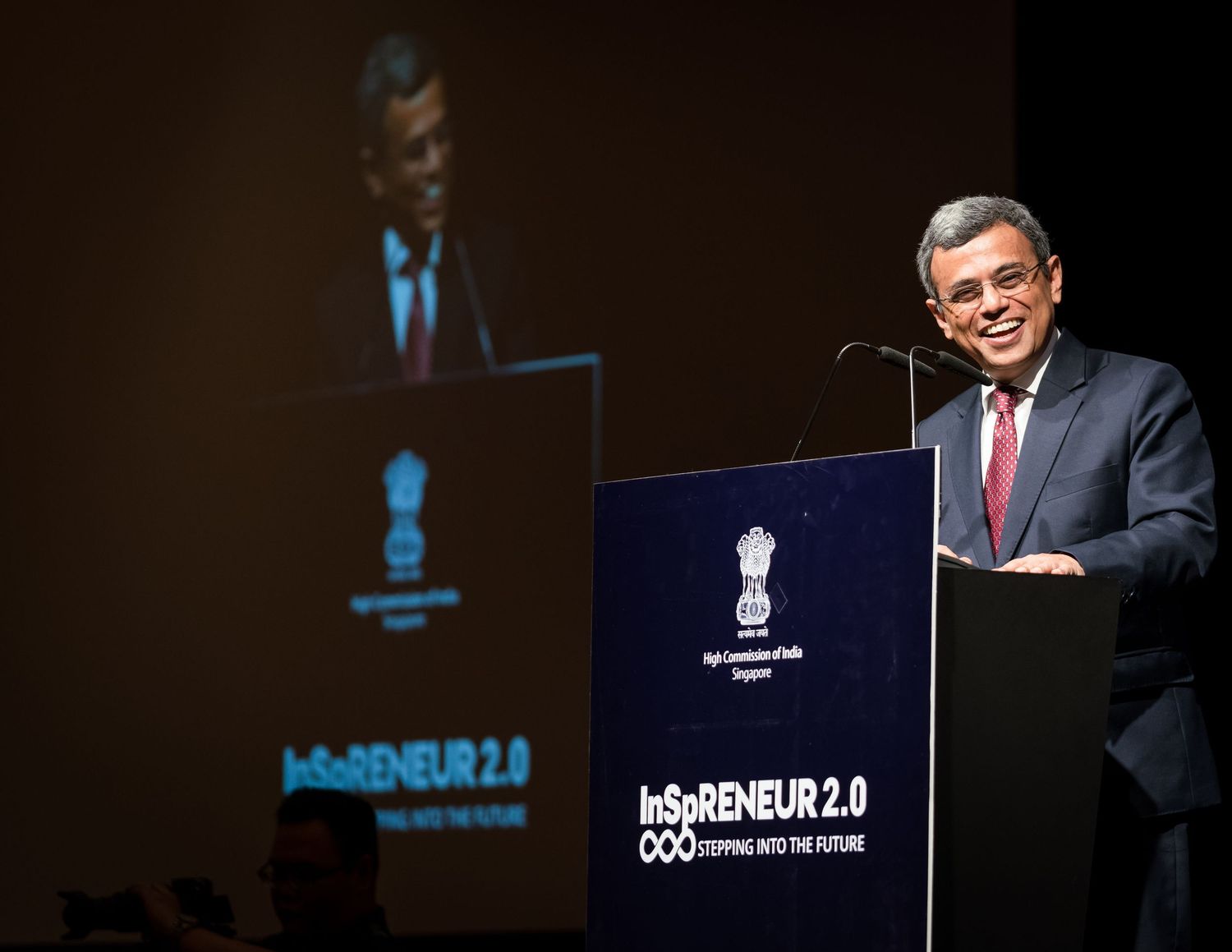 A speaker delivers a presentation at InSoRENEUR 2.0 event at a podium with the High Commission of India Singapore logo.