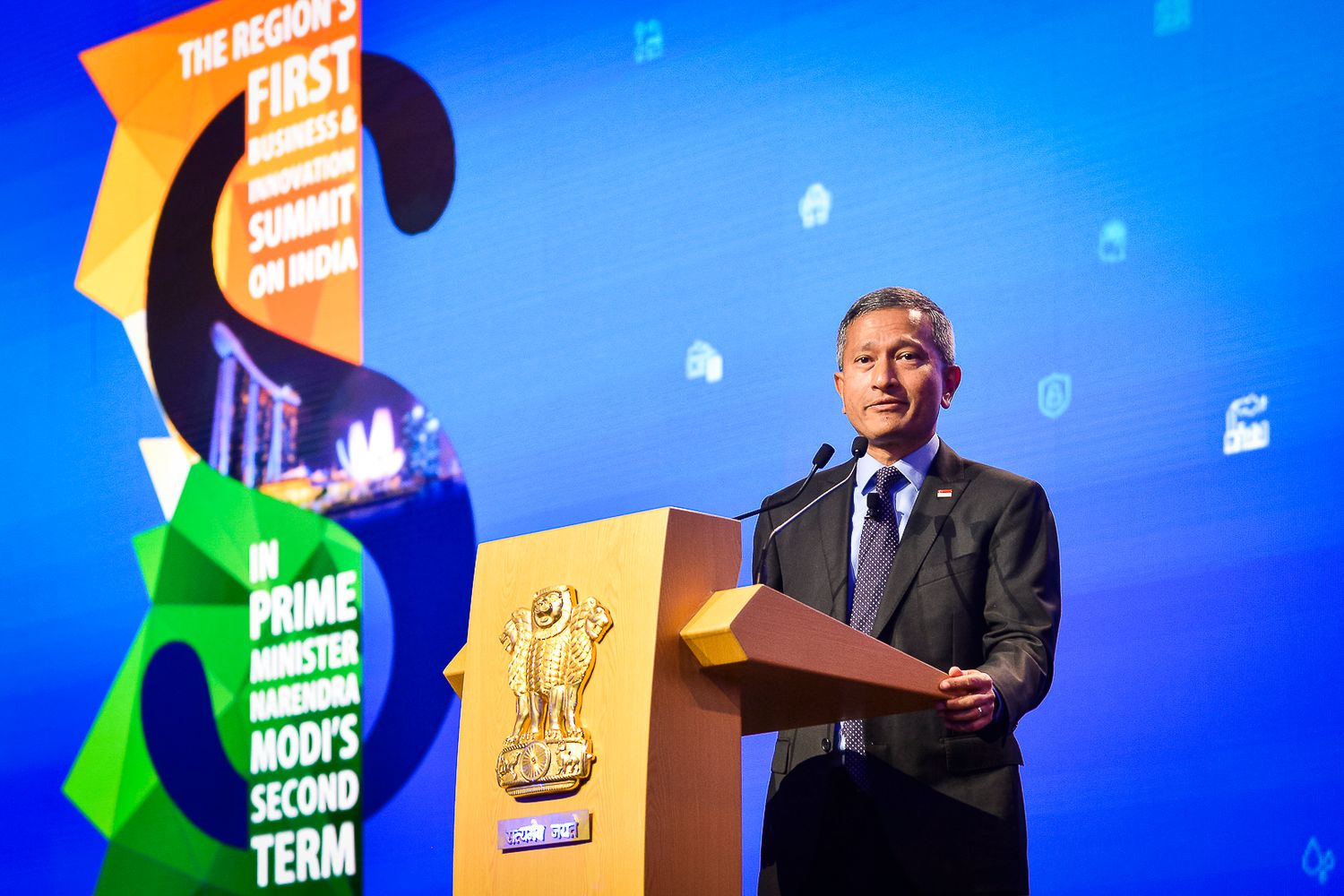 A man in a suit delivers a speech at a podium during a Prime Minister Modi summit event.