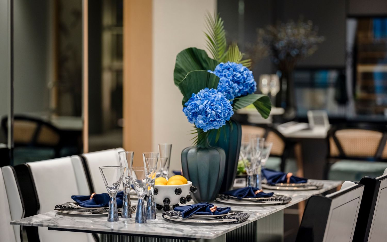 Elegant dining table set with blue hydrangea centerpiece and crystal glassware.