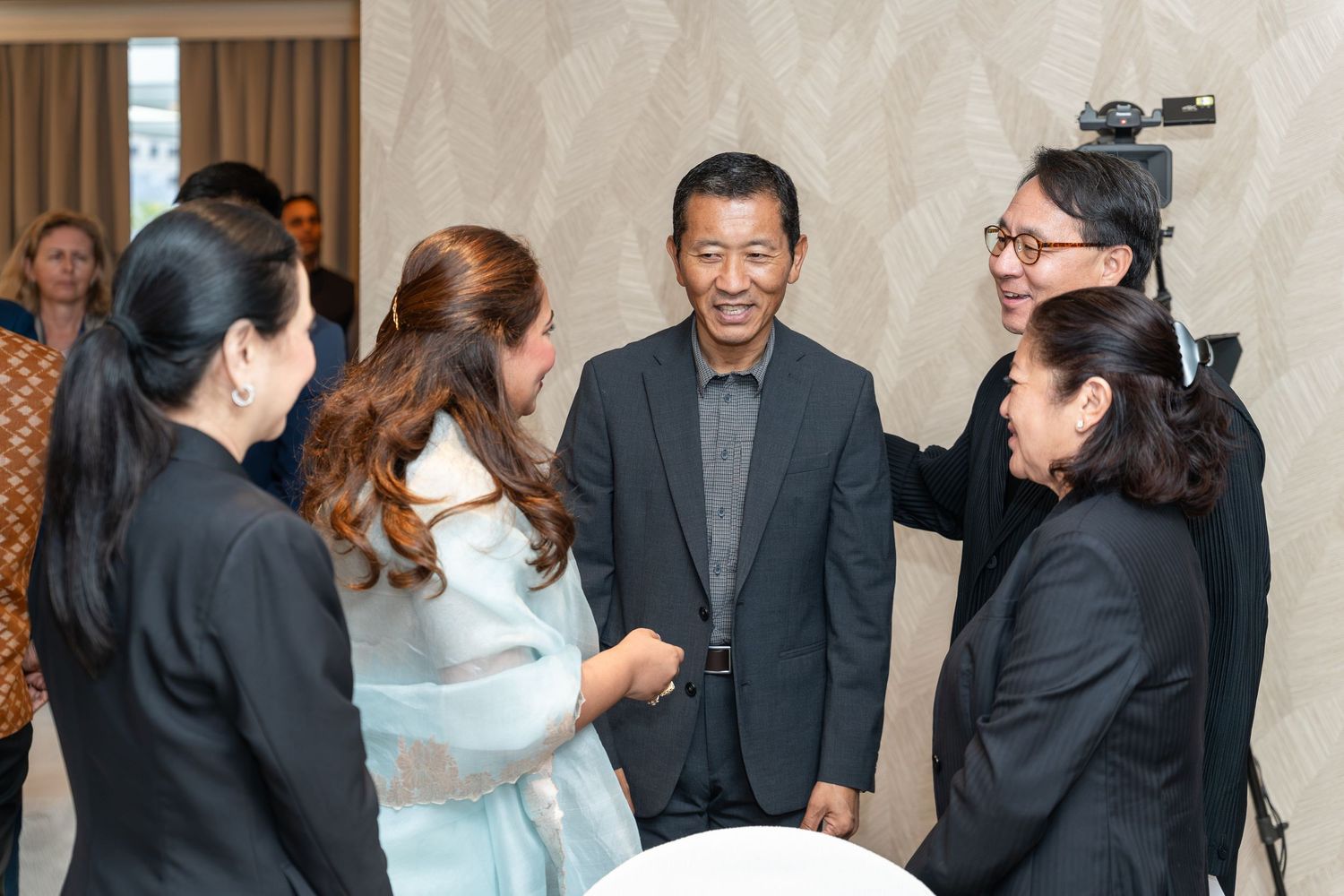 A group of smiling professionals networking at a formal event in a modern venue.