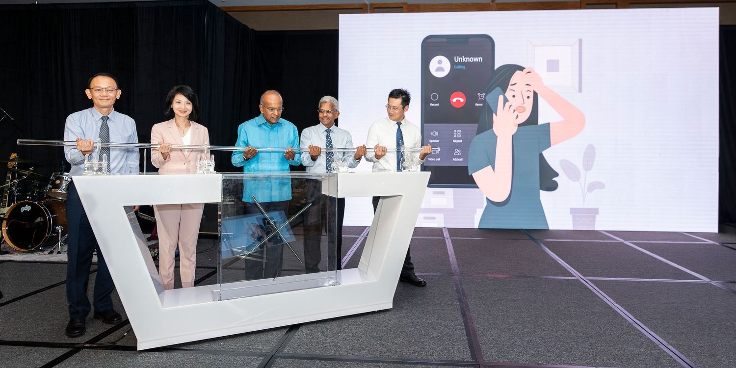 Five professionals launch a mobile app at a tech event with a glowing screen display in Singapore.