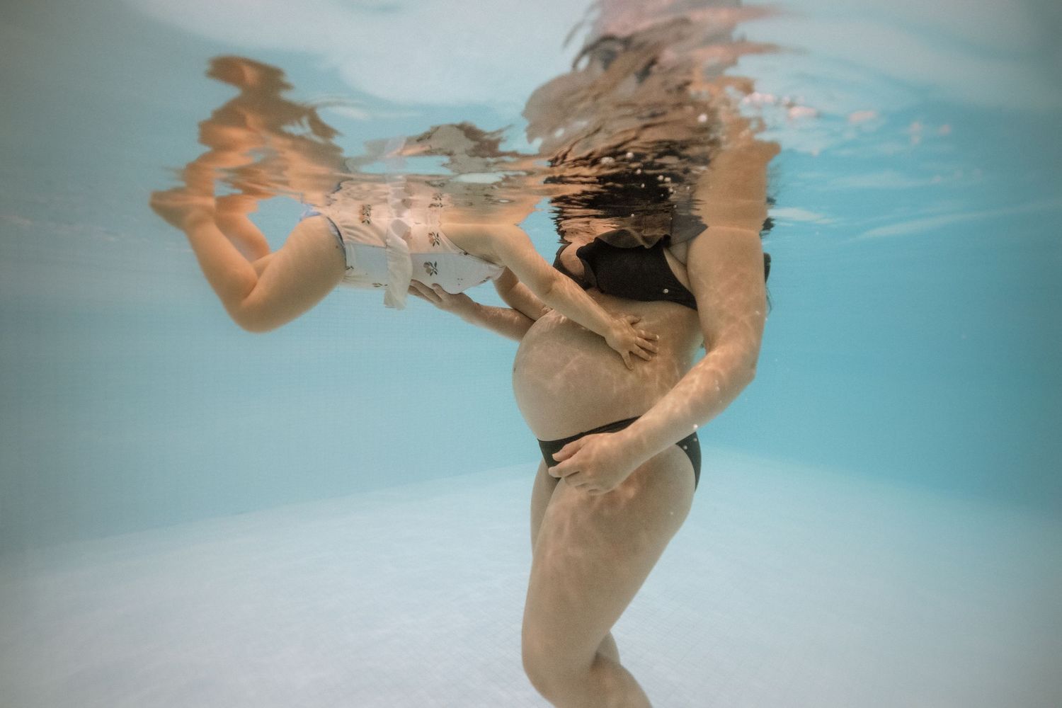 Séance photo aquatique à Vevey, future maman  et enfant dans l’eau pendant une séance grossesse