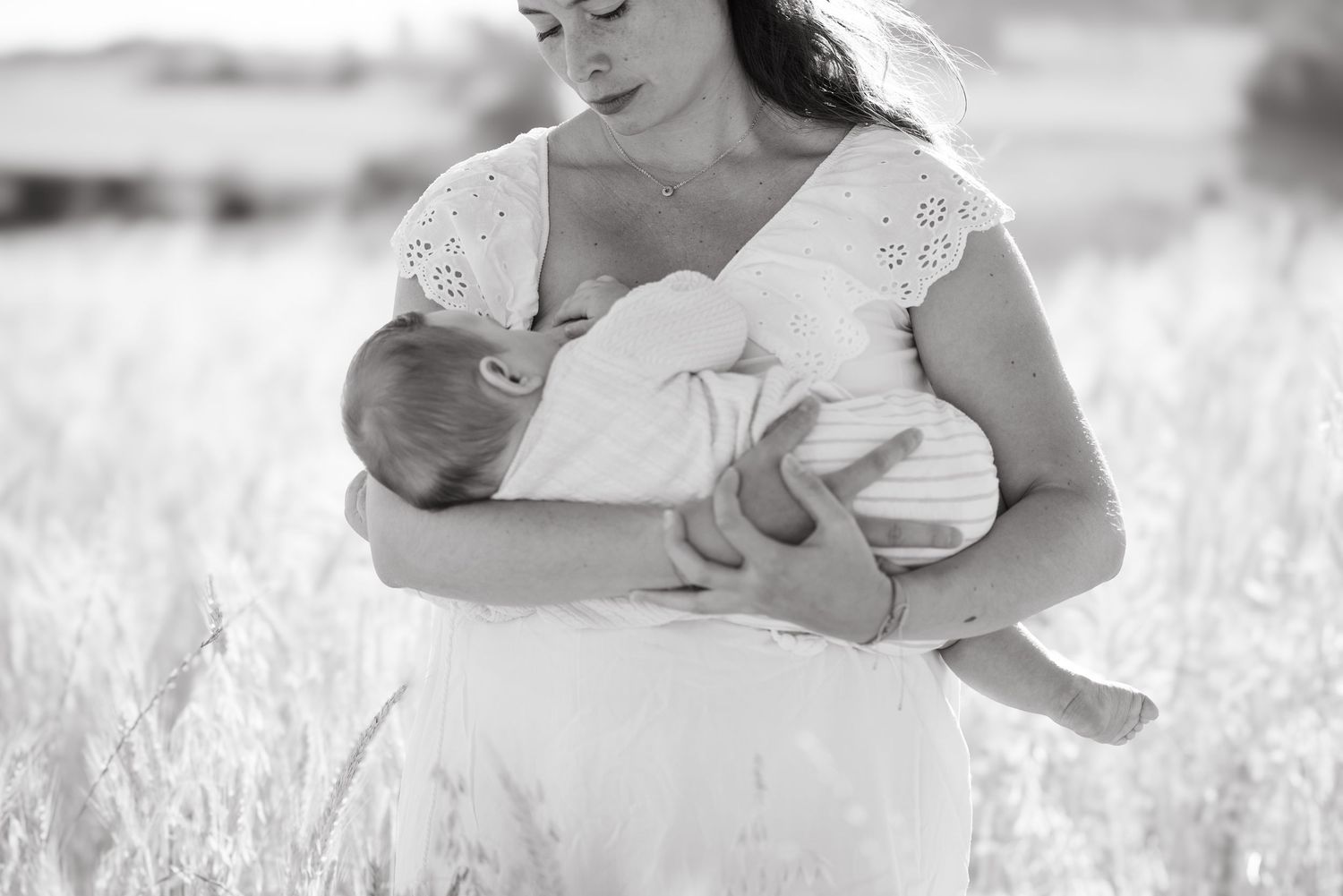 Séance photo maternité en extérieur à Vevey, une maman allaite son bébé dans une lumière douce et naturelle.
