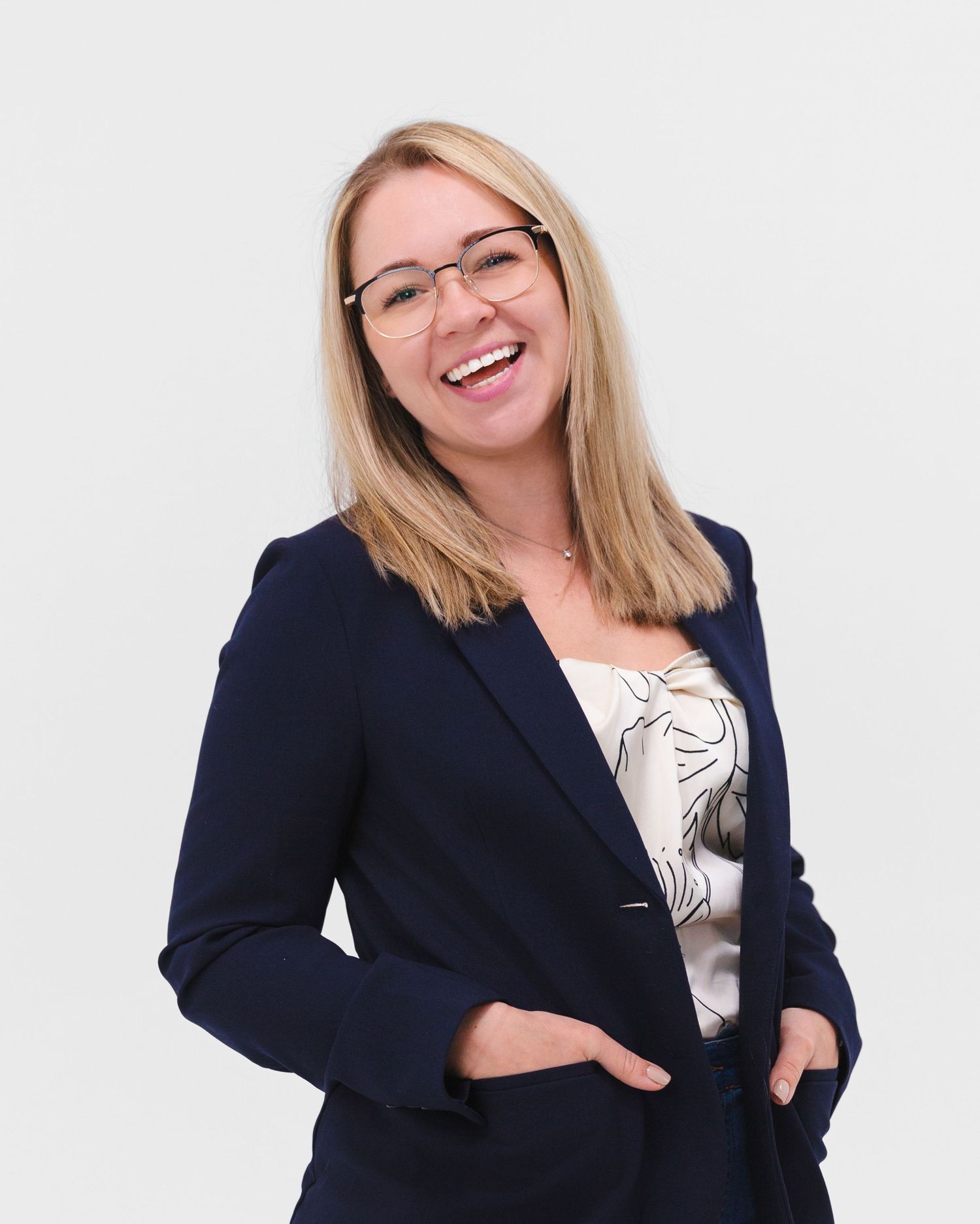 Professional headshot of woman in navy blazer smiling against white background. Round Rock head shot photographer.