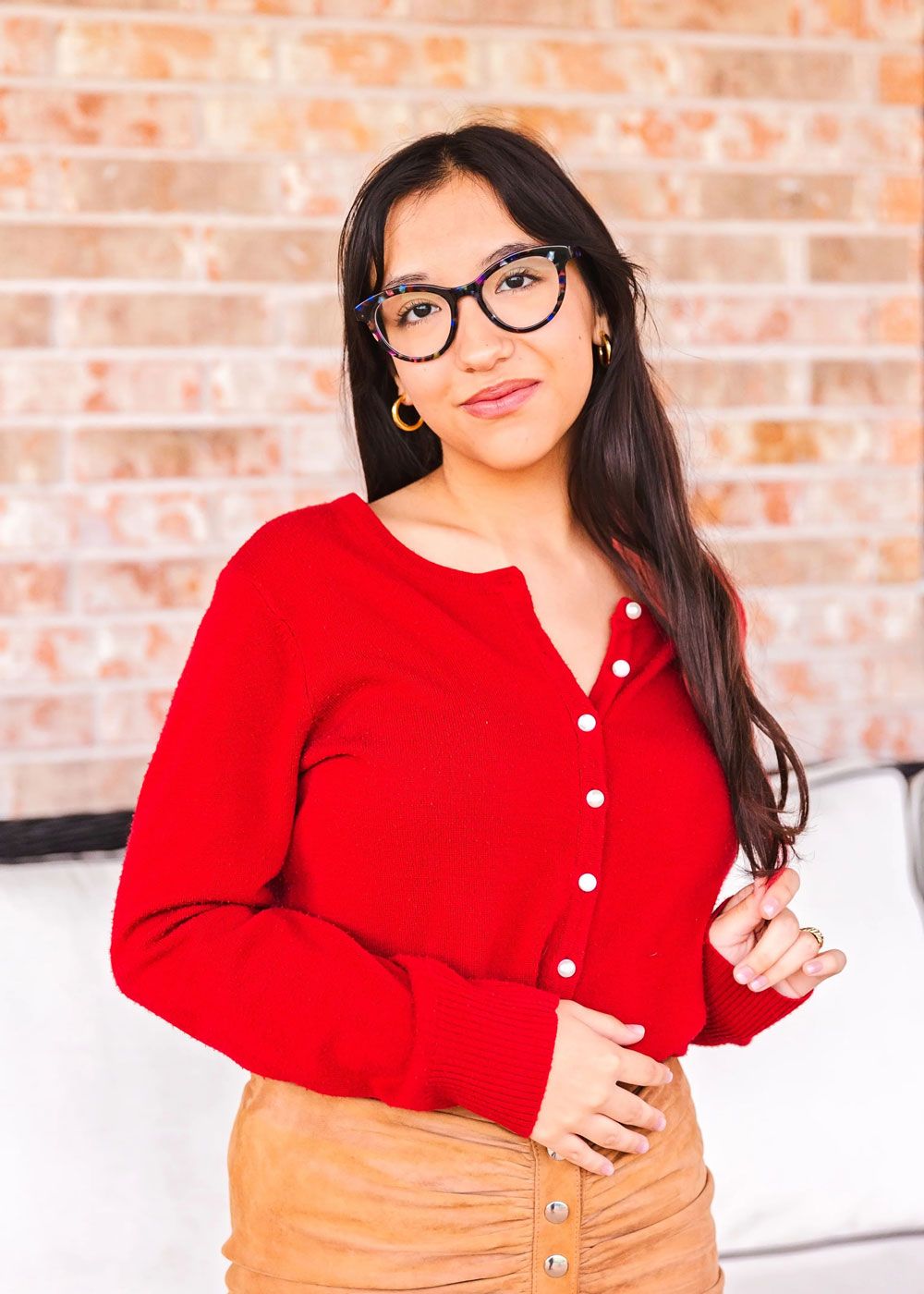 Portrait series against a brick wall featuring someone in a red button-up top.