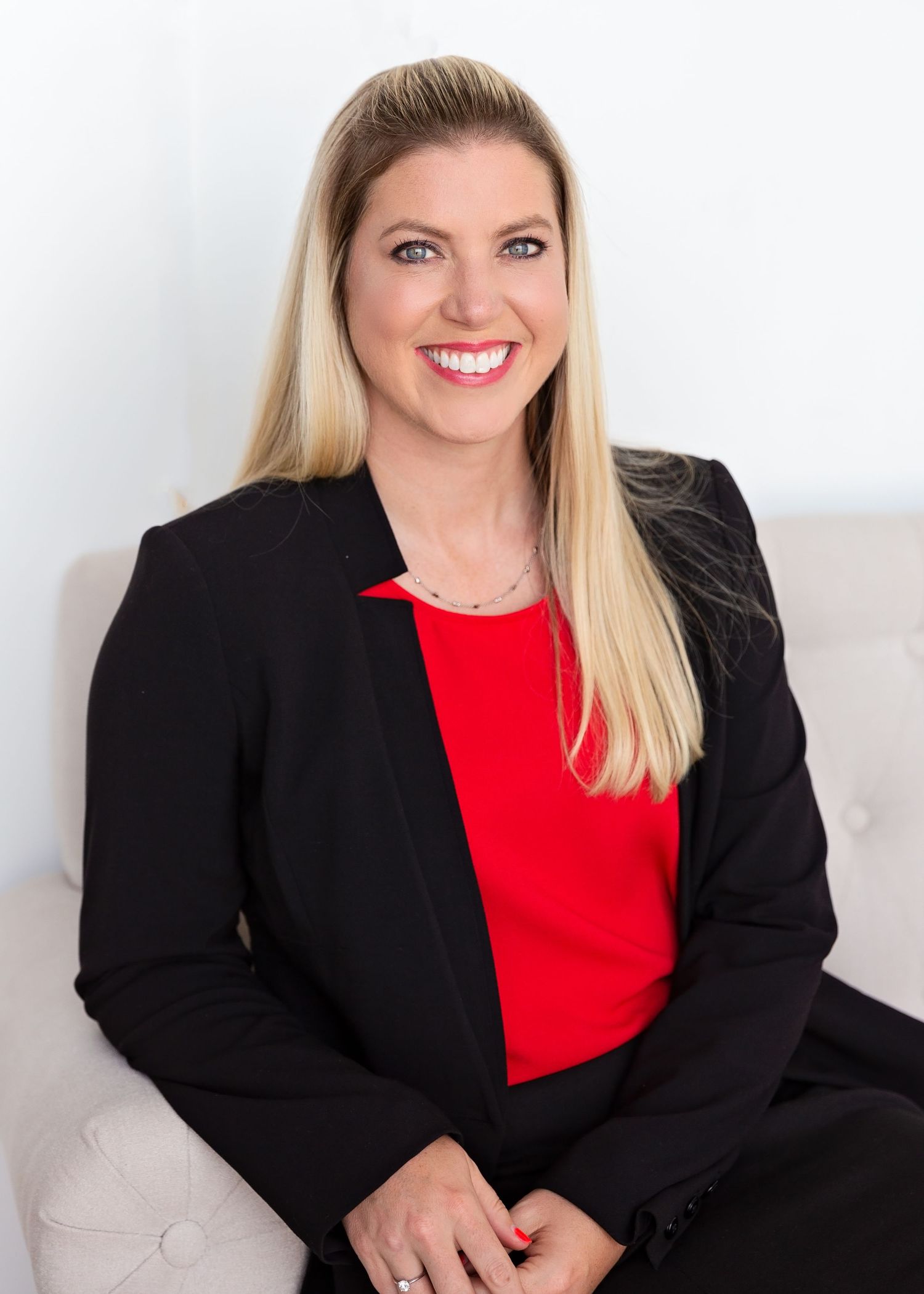Professional business portraits featuring a black blazer and red top against a light background.