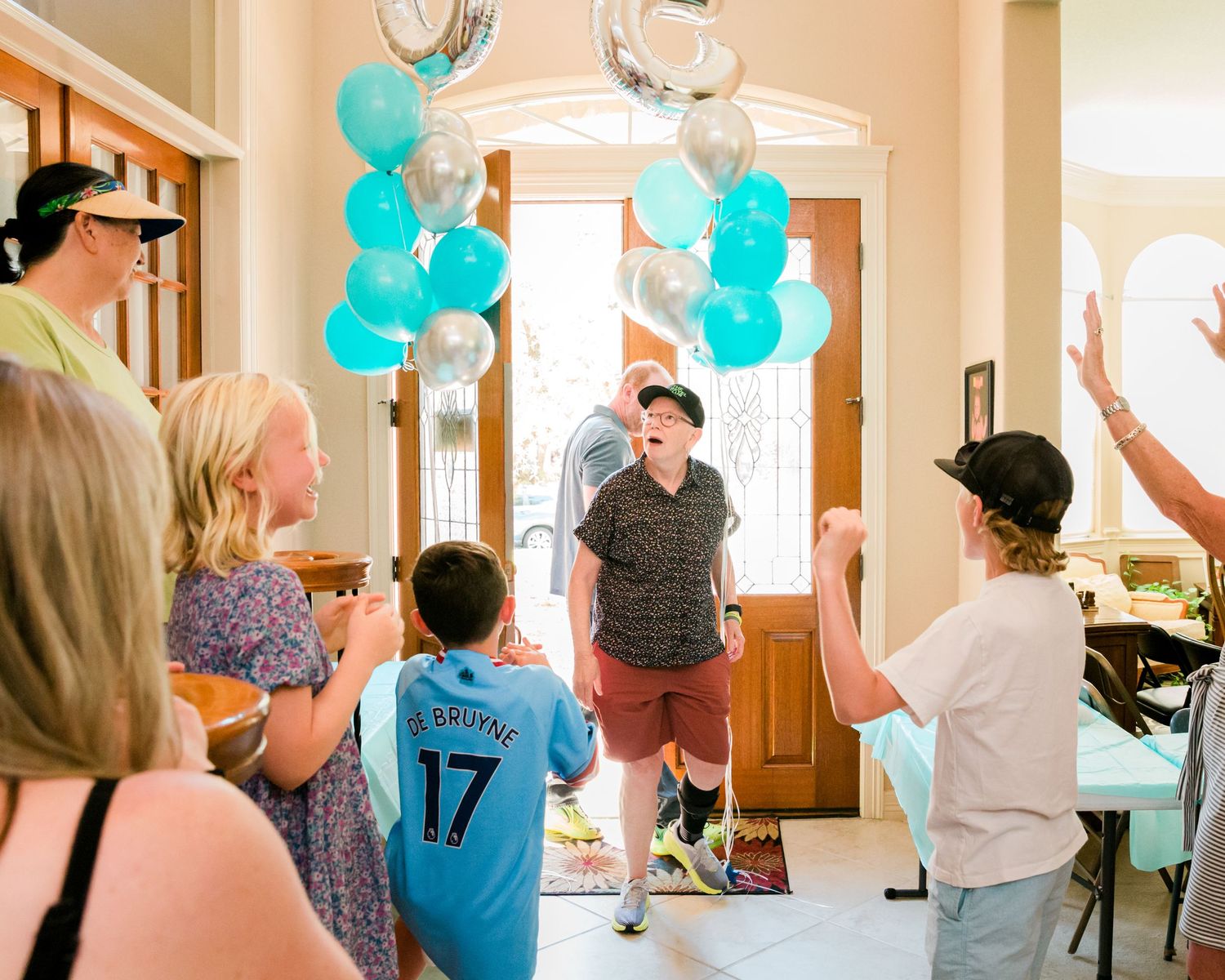 Indoor party scene with teal balloons decorating a hallway for a celebration.