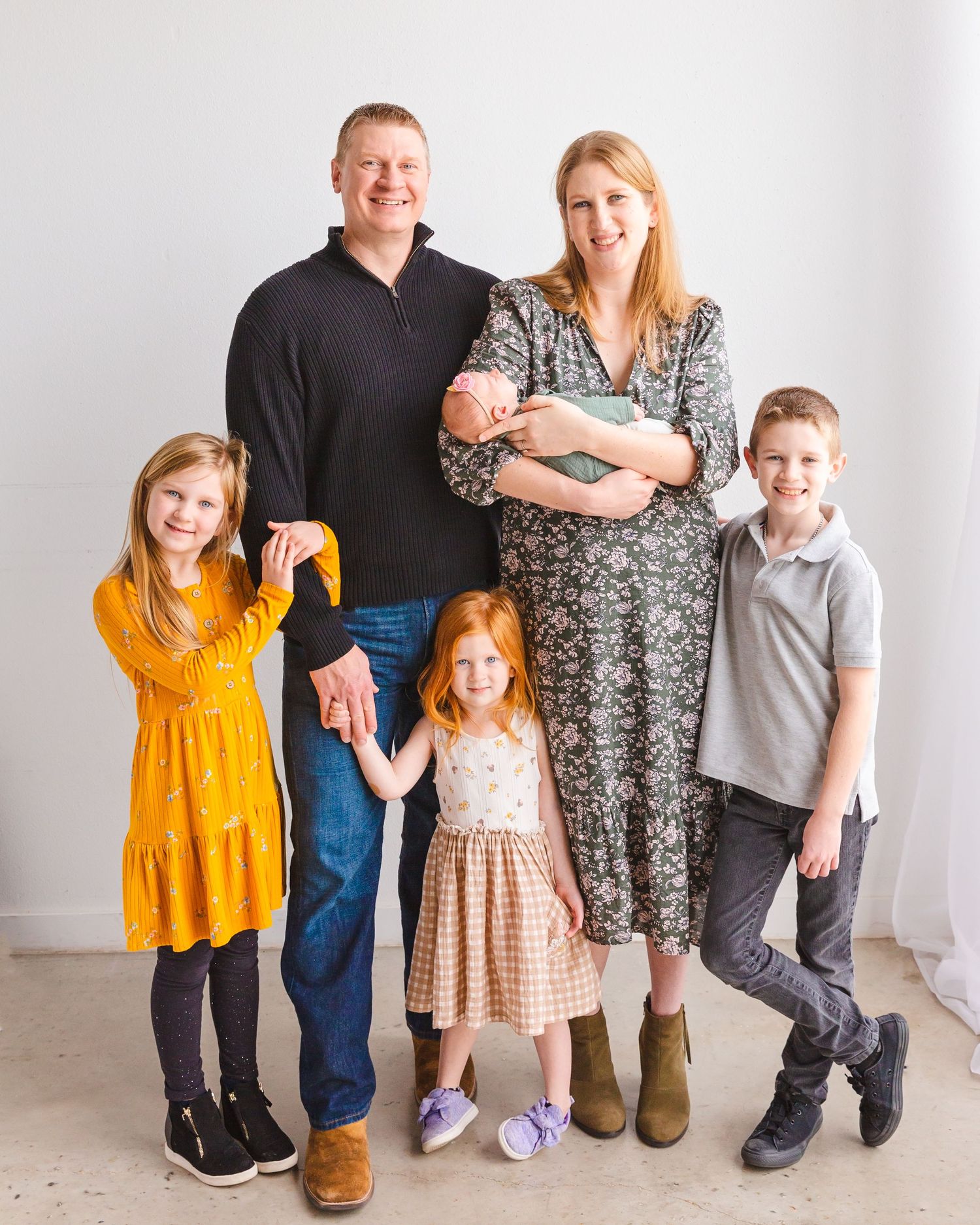 A studio family portrait with coordinated outfits against a white background.