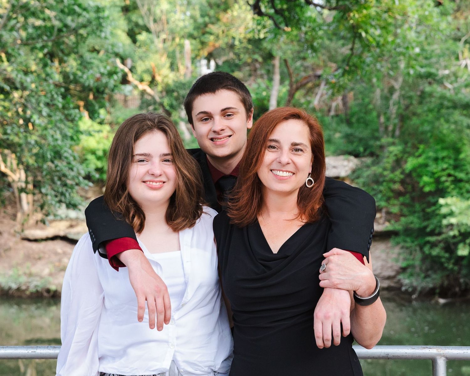 A group poses together outdoors near a lake on a sunny day.