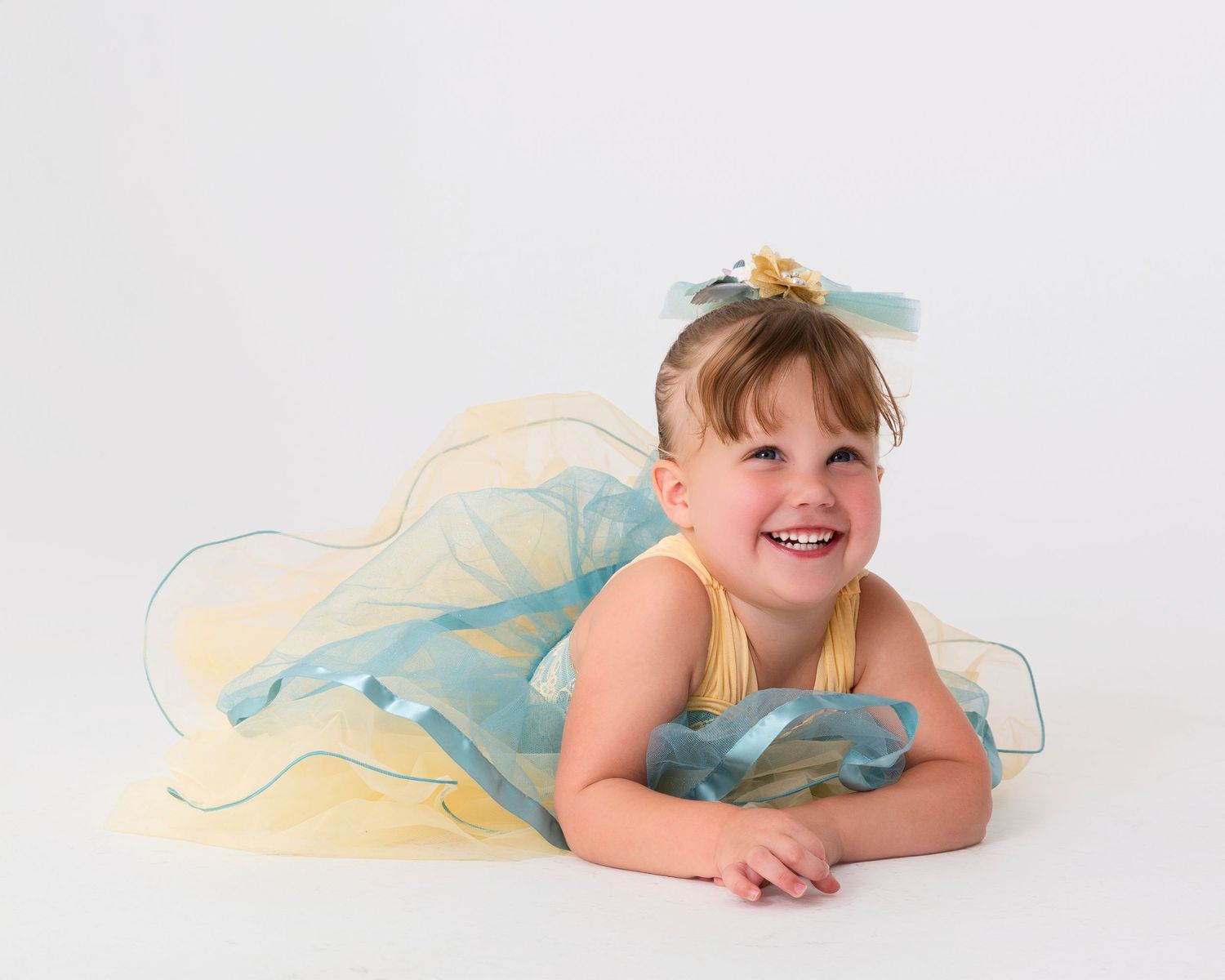 Dancer in pastel tulle dress poses elegantly on white background.