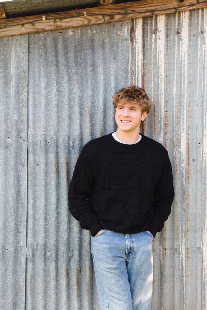 Casual portrait series against corrugated metal wall in black sweater.
