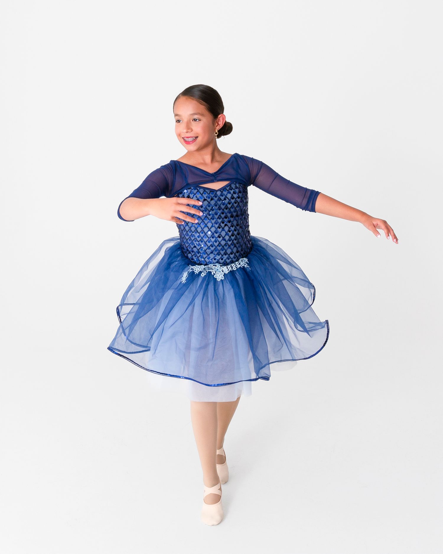 Dancer in blue sequined tutu dress performs graceful ballet movements.