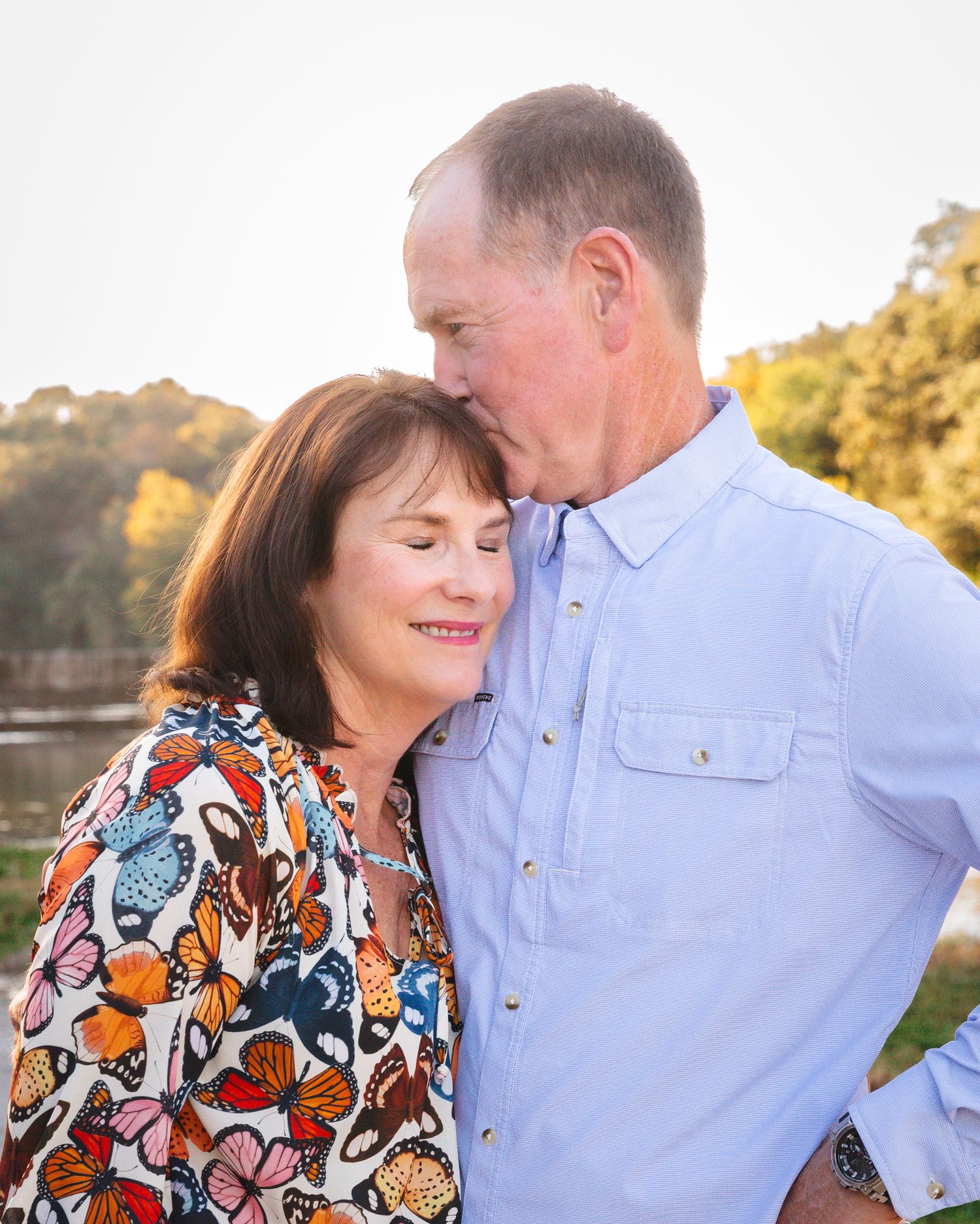 A couple shares an intimate moment outdoors with the woman wearing a colorful butterfly print top.