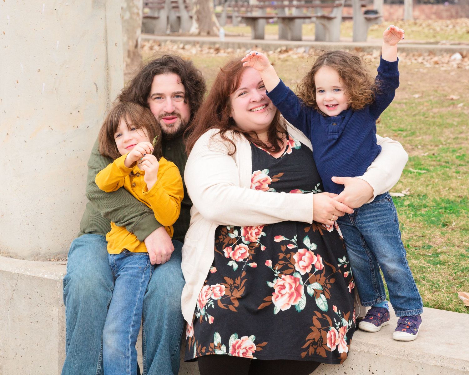 A cheerful family gathering poses on concrete steps outdoors during a photo session.