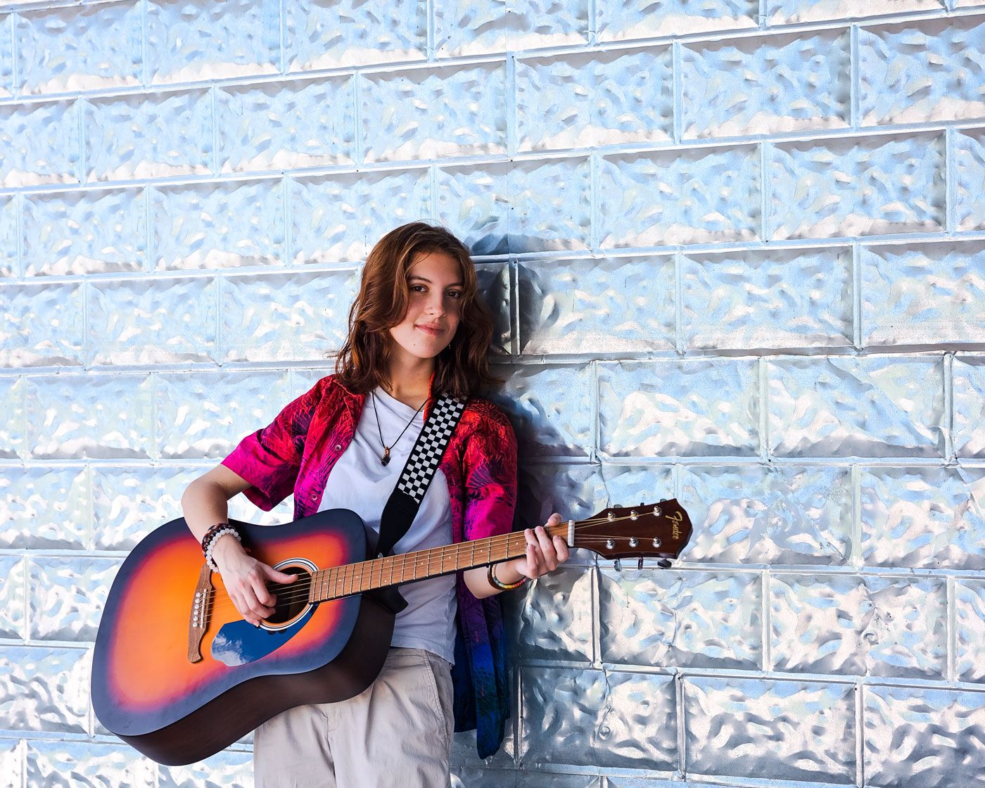 Series of artistic shots playing acoustic guitar against textured wall.