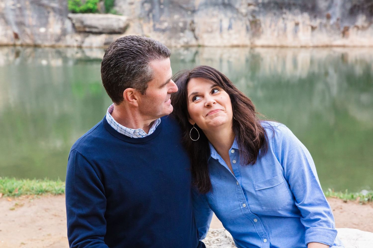 Couple sitting by a lake sharing tender moments together in nature.