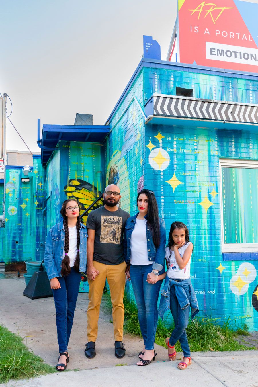 Group poses against vibrant blue wall with artistic text and sparkle designs.