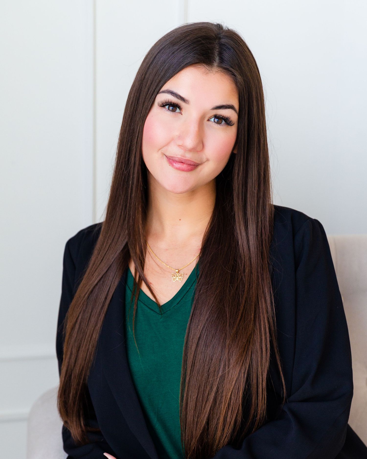 Professional headshots of someone in a dark blazer and emerald green top against a light background.
