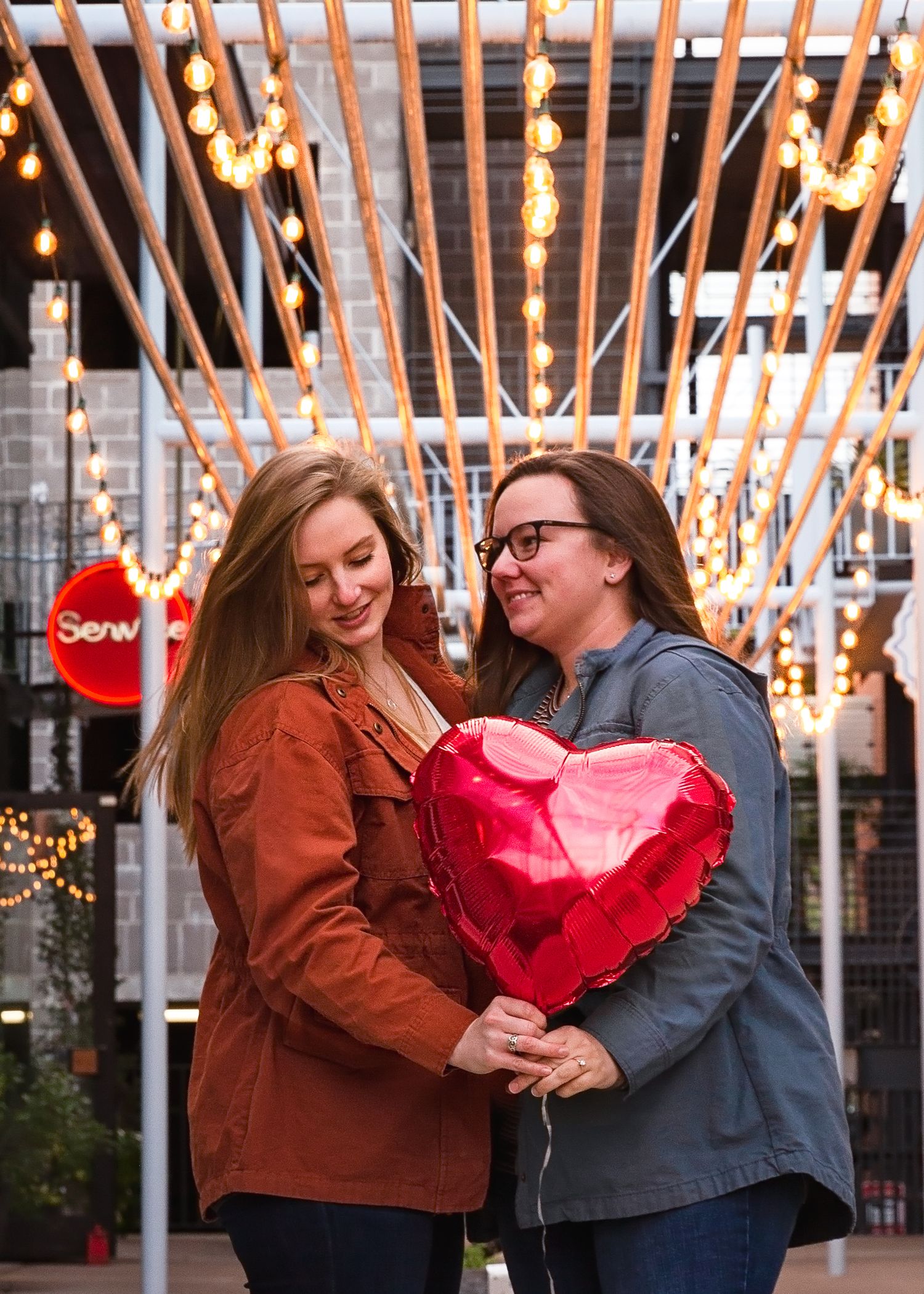Group enjoying playful moments under illuminated string lights in an urban setting.