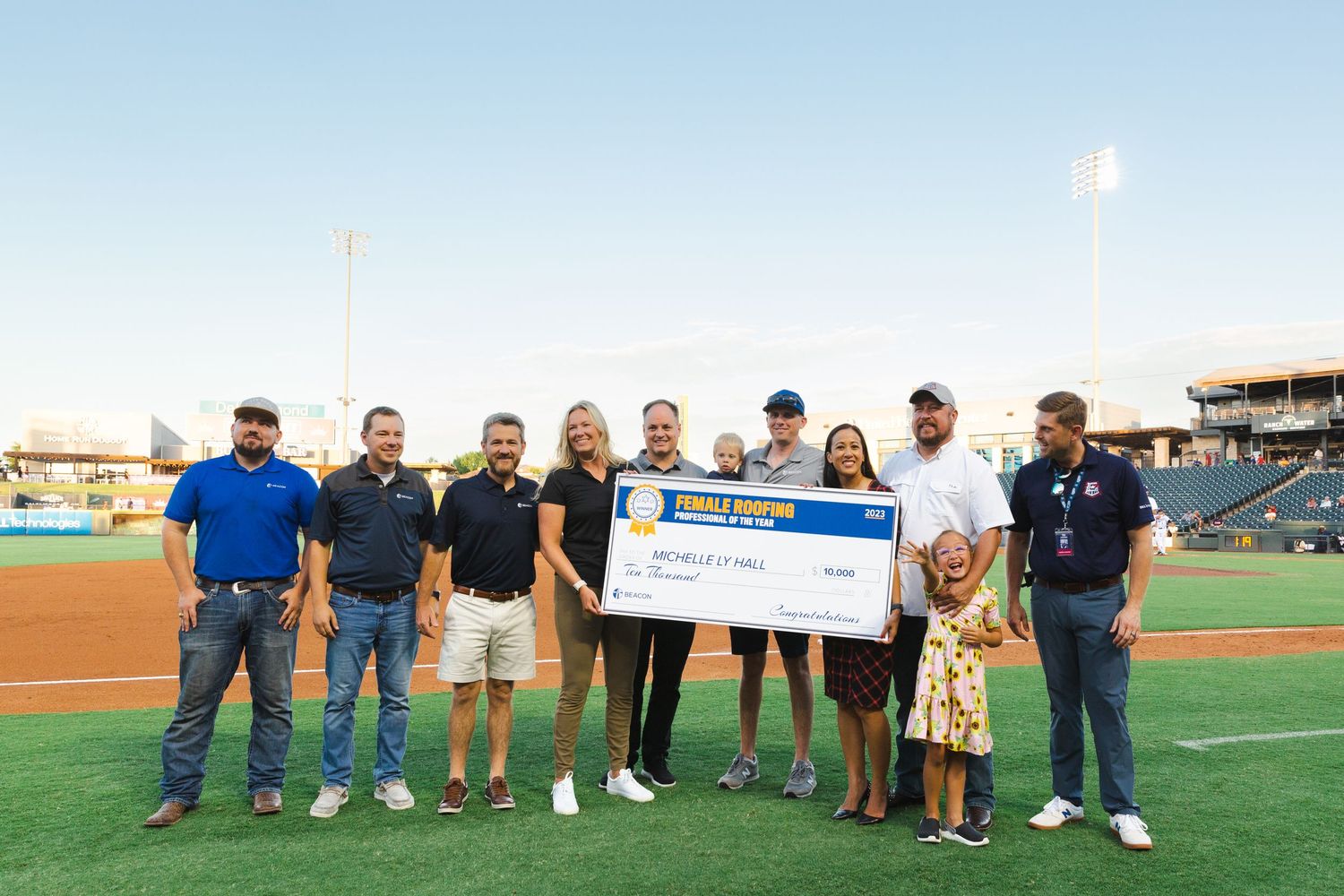 Group of people presenting large check at baseball stadium.
