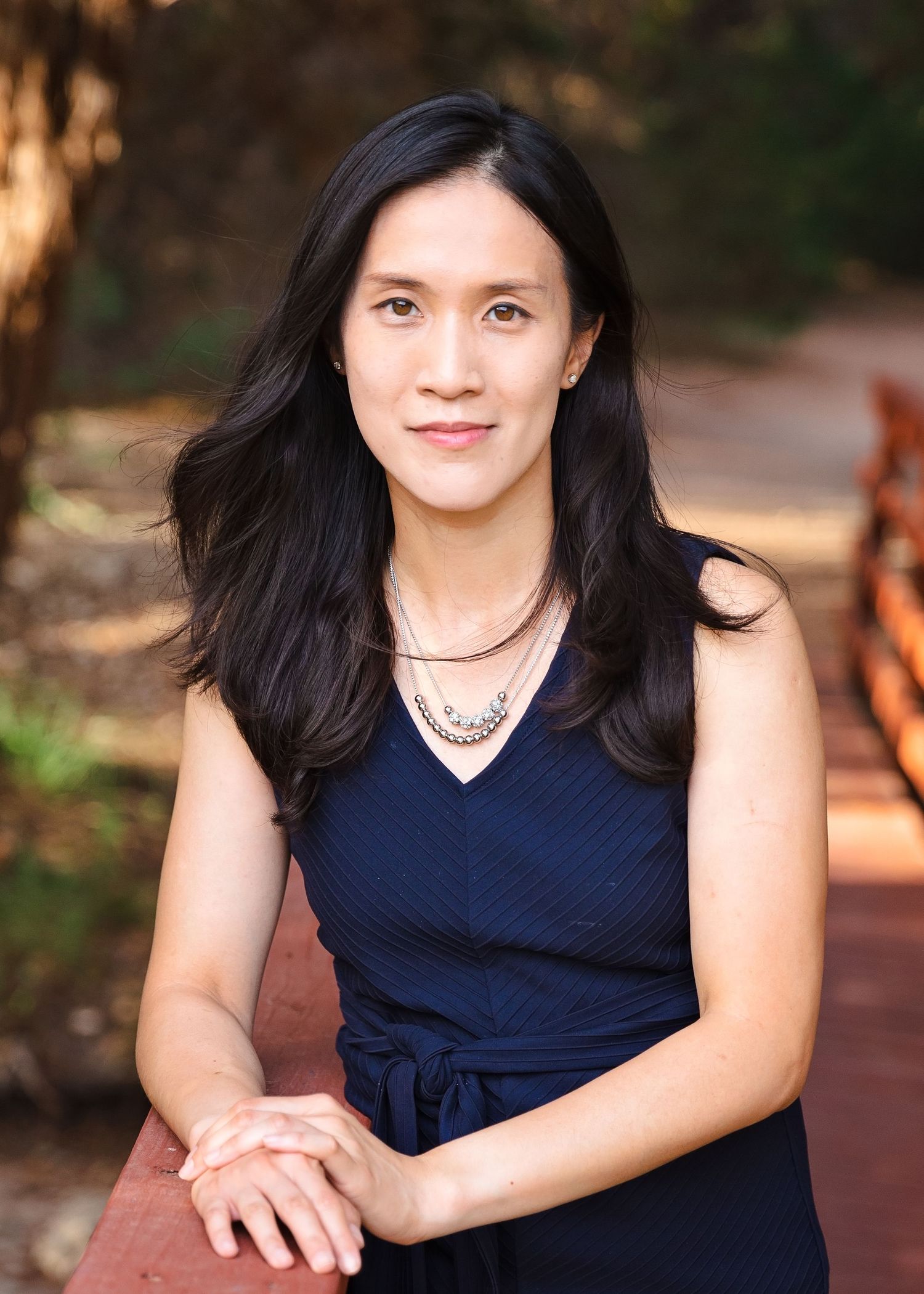 Series of professional portraits in a navy dress against an outdoor setting.