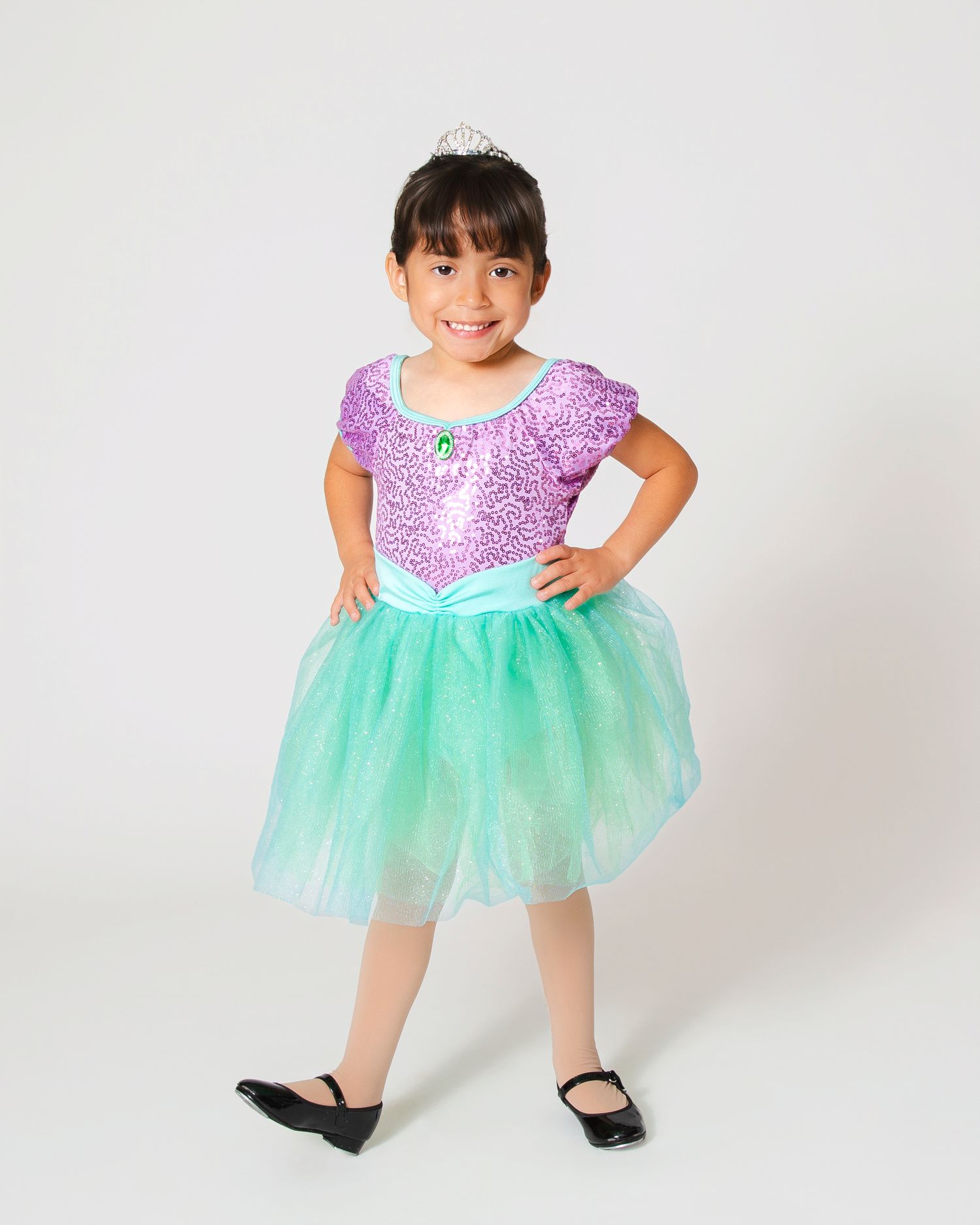 Dancer wearing sparkly mint green tutu dress poses playfully in studio.