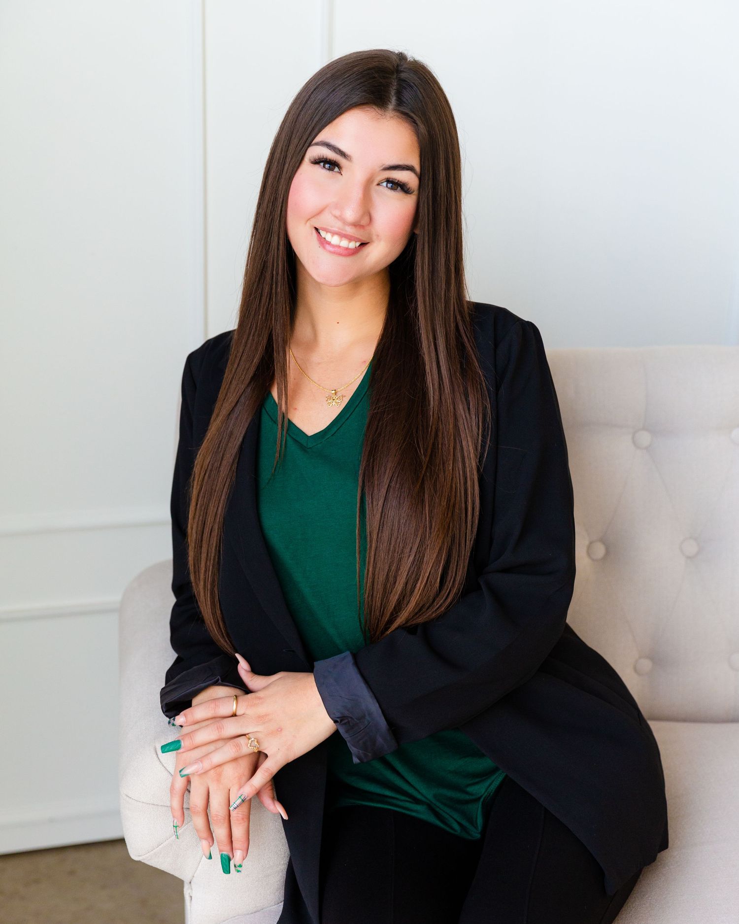 Professional portraits of person wearing green top and black blazer in studio setting.