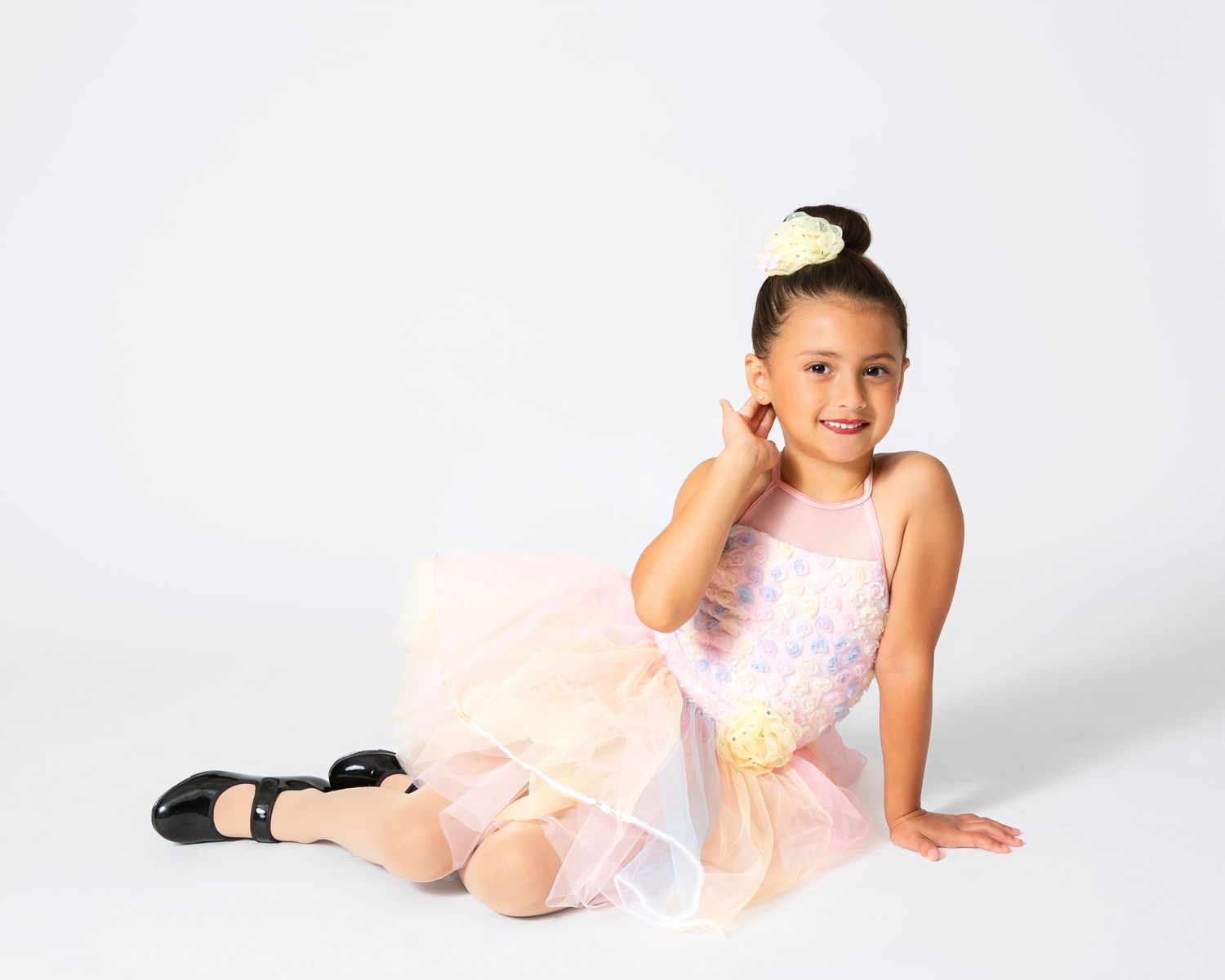 Dancer in peach-colored tutu demonstrates elegant ballet poses against white backdrop.
