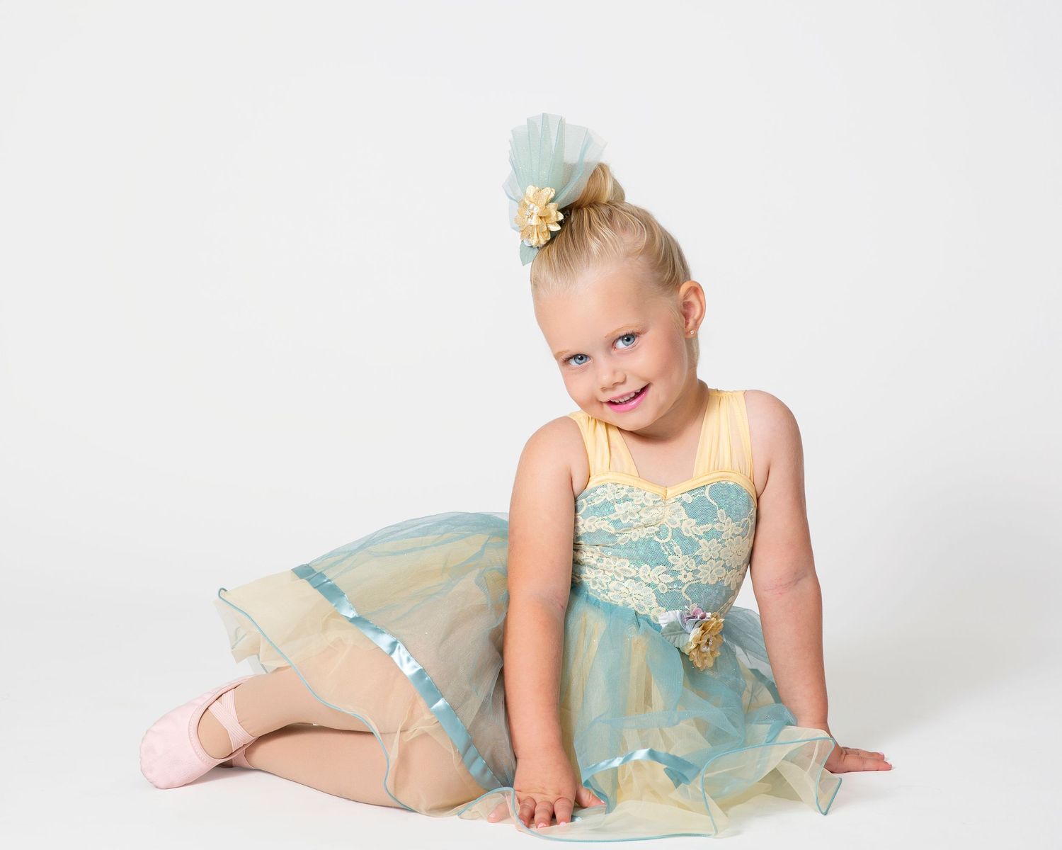 Dancer in mint green tulle costume posing gracefully on white floor.