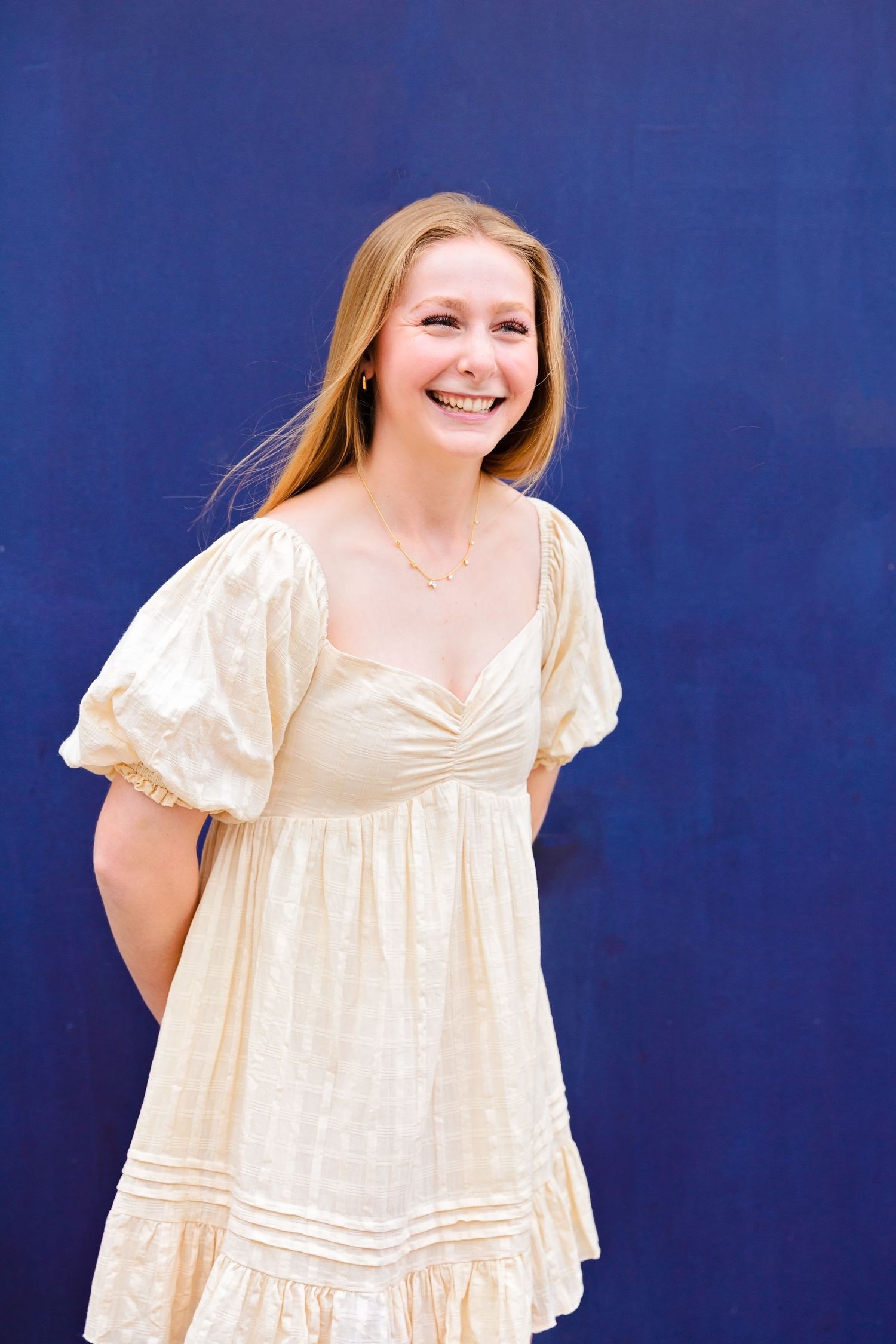 A series of photos showing a person in a flowing white summer dress against a blue background. Senior portrait session in Round Rock, TX