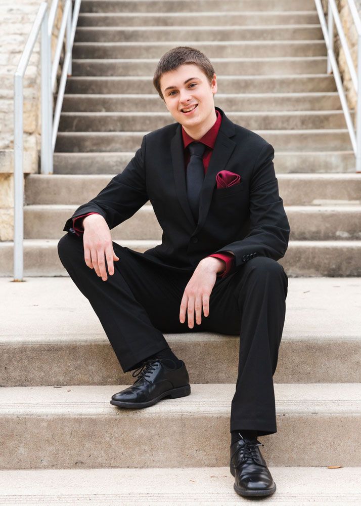 Formal portraits on concrete steps wearing black suit and red bowtie.