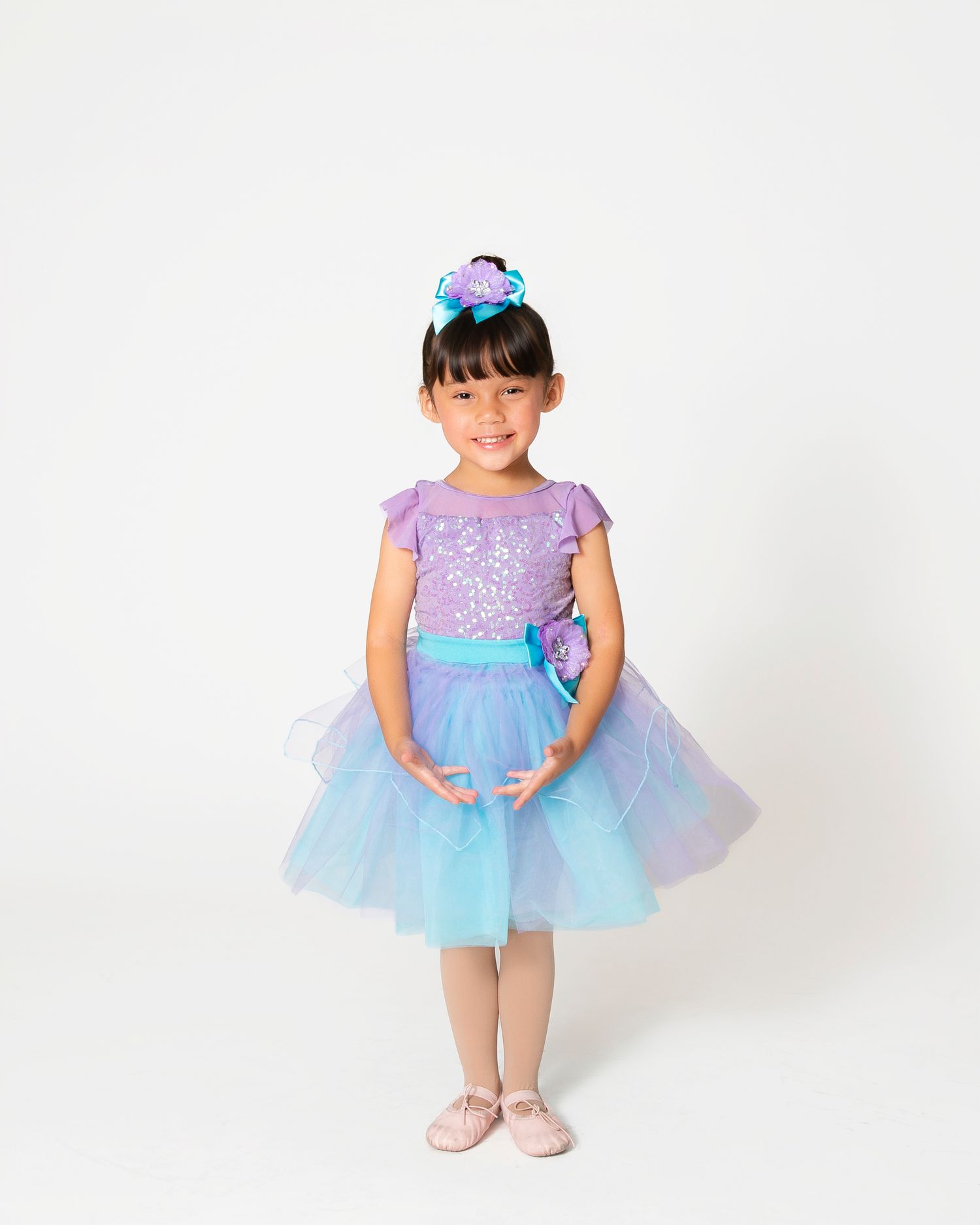 Tiny dancer in lavender and blue tutu dress shows graceful ballet positions.
