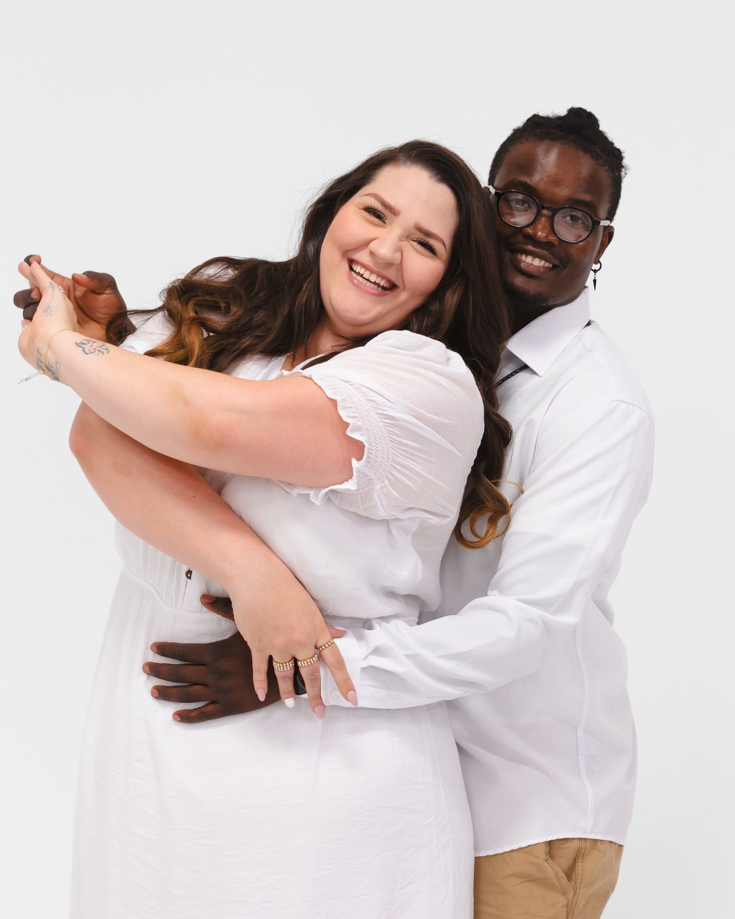 Couple in matching white shirts embraces during studio photography session.