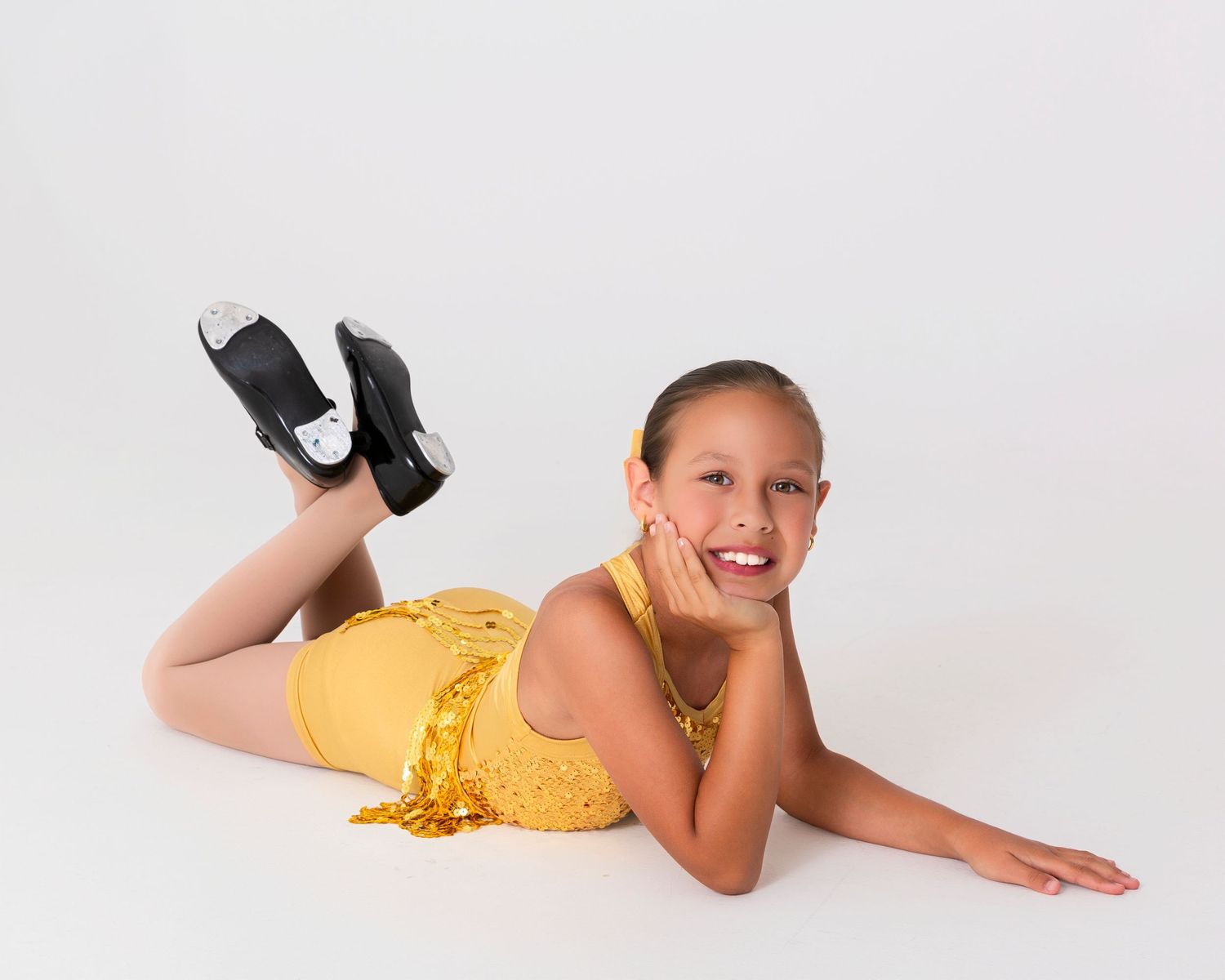 Dancer in yellow sequined costume strikes playful poses on studio floor.