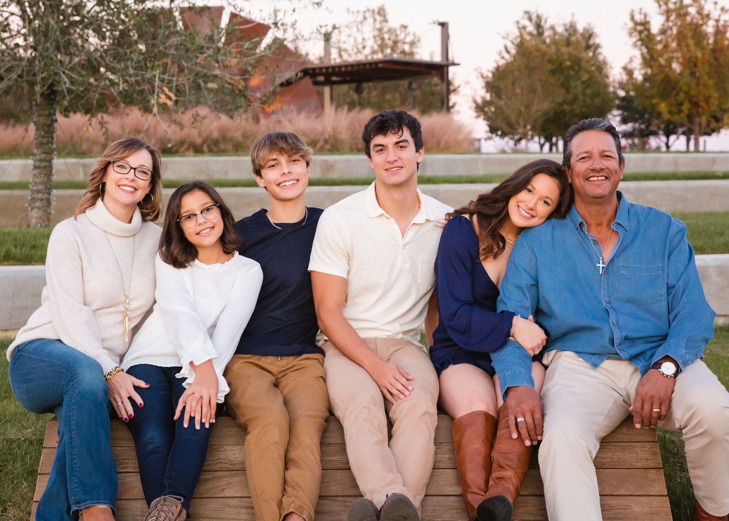 Family members sitting together on wooden steps during golden hour.