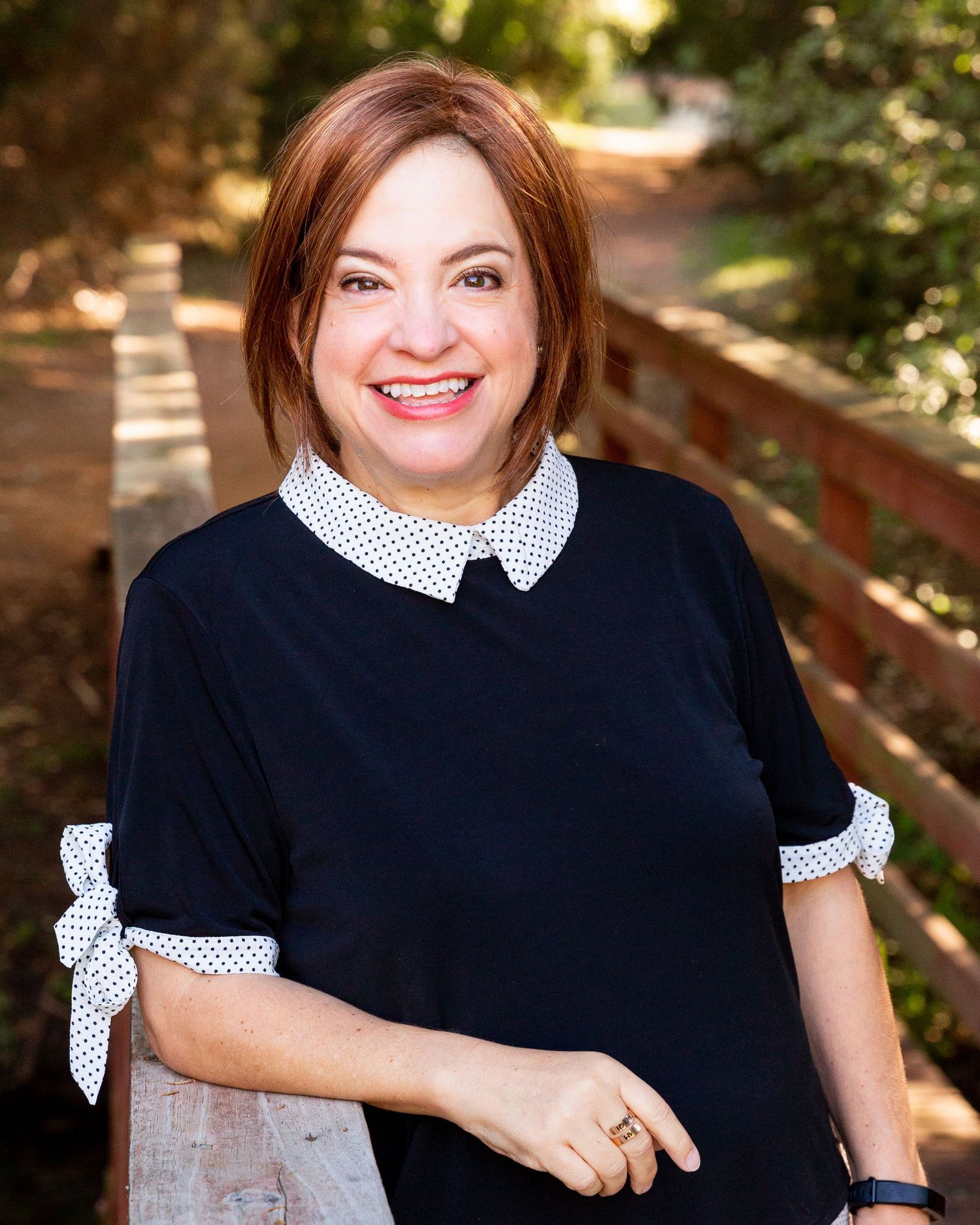 Outdoor portraits in navy dress with polka dot collar against natural background.