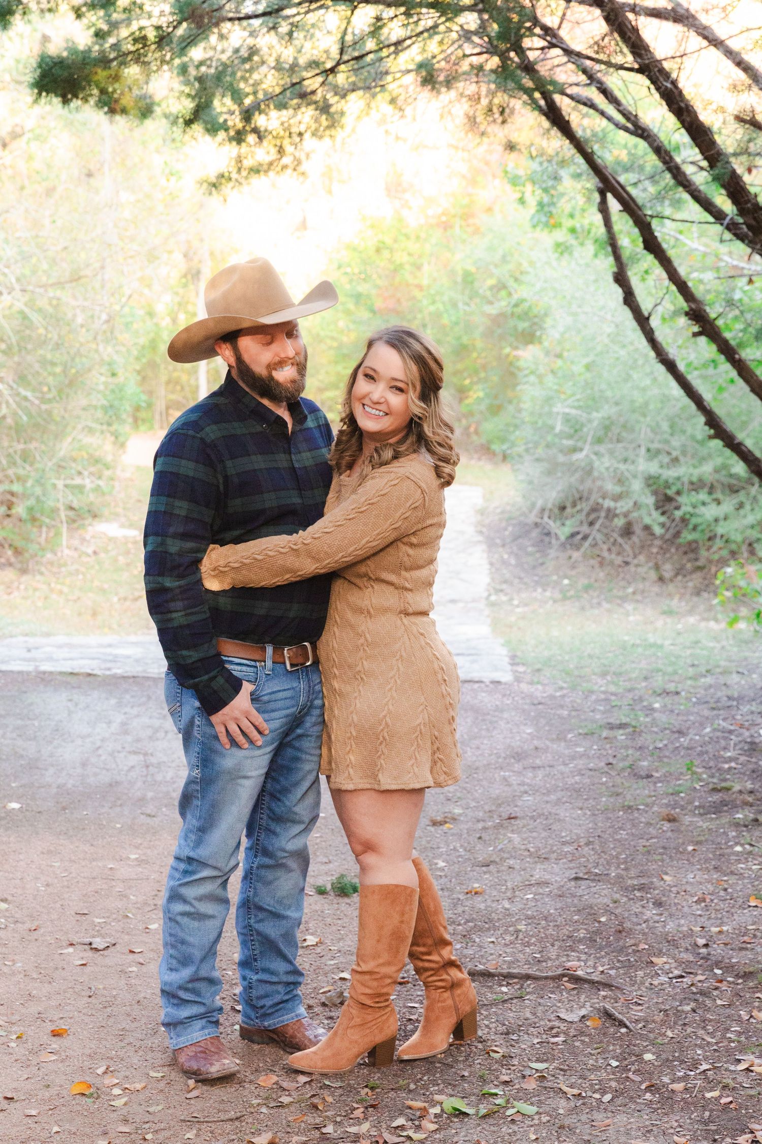 A couple shares tender moments on a wooded path during an autumn photoshoot.
