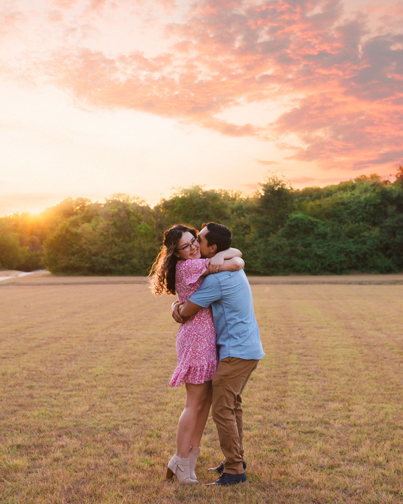 Two children embrace in a field during golden sunset.