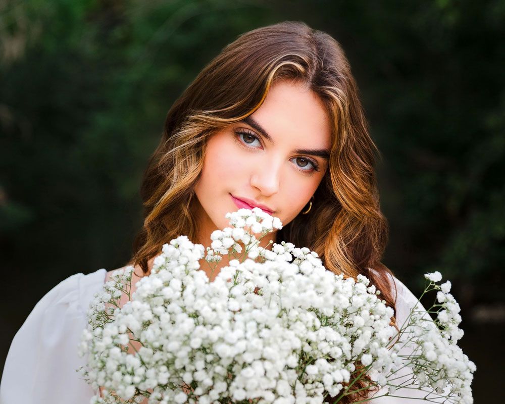 Close-up portrait with baby's breath flowers creating an ethereal effect against dark backdrop. Senior portrait in Pflugerville.