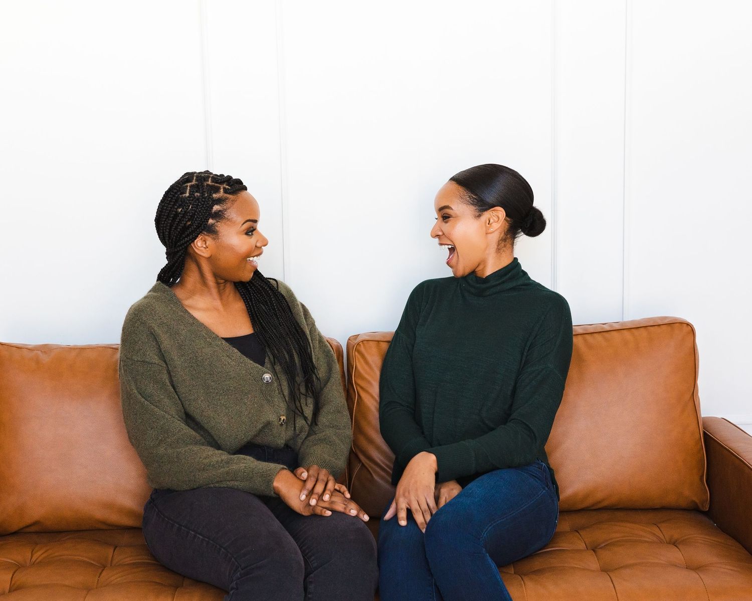 Friends sharing a casual moment while relaxing on a brown leather sofa.